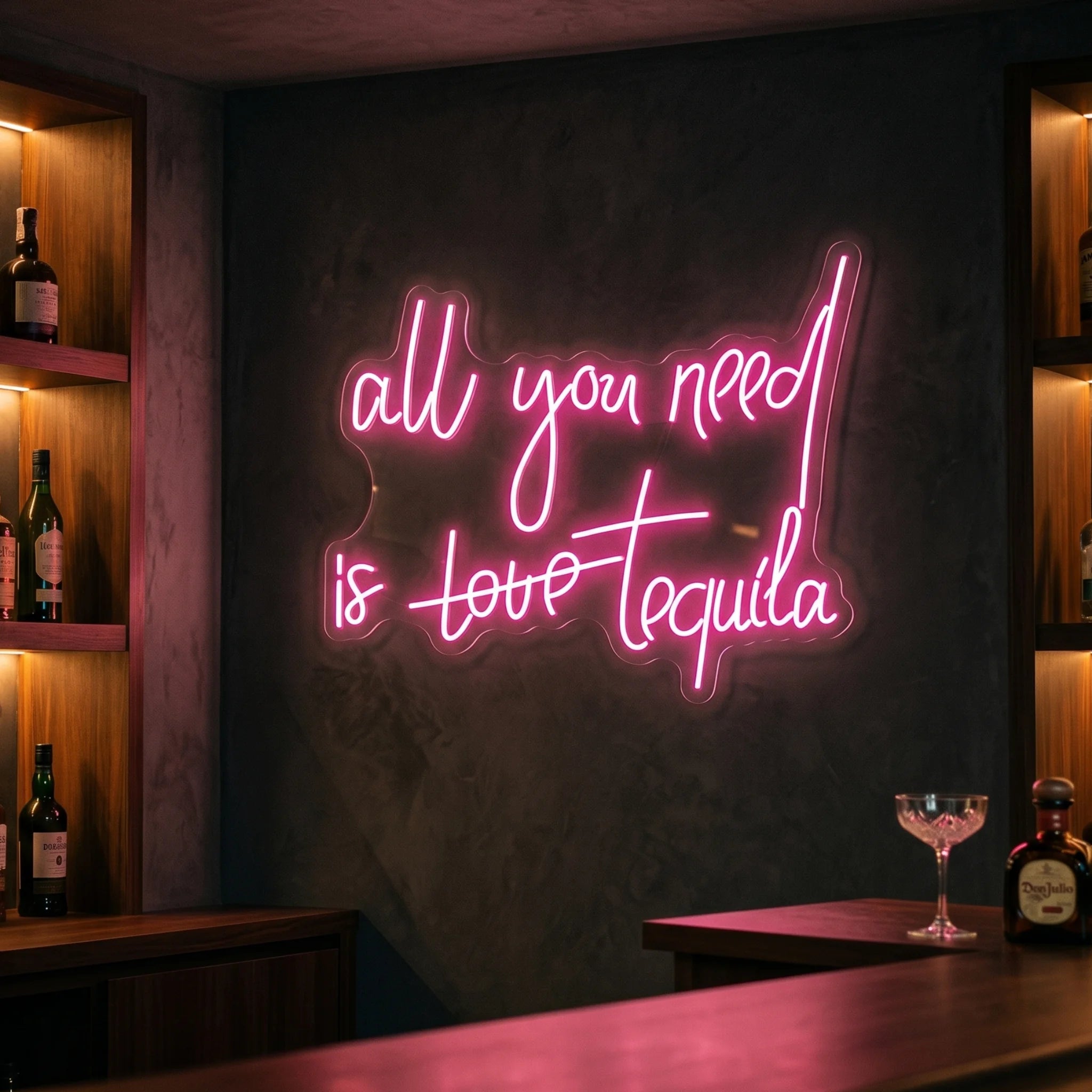 Photo of the 'All you need is tequila' neon sign glowing in deep pink against a styled interior wall.