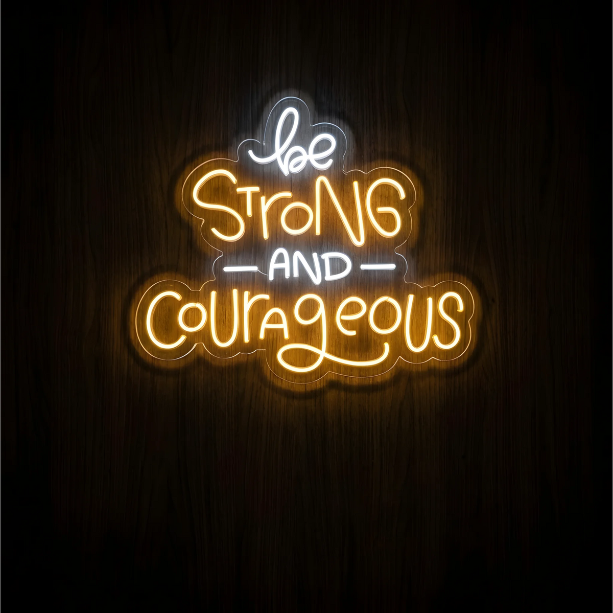 Be Strong and Courageous LED Neon Sign with warm yellow βStrongβ and βCourageousβ lettering and white βbeβ and βANDβ on clear acrylic against a dark wood background, suited to bedrooms and home offices.