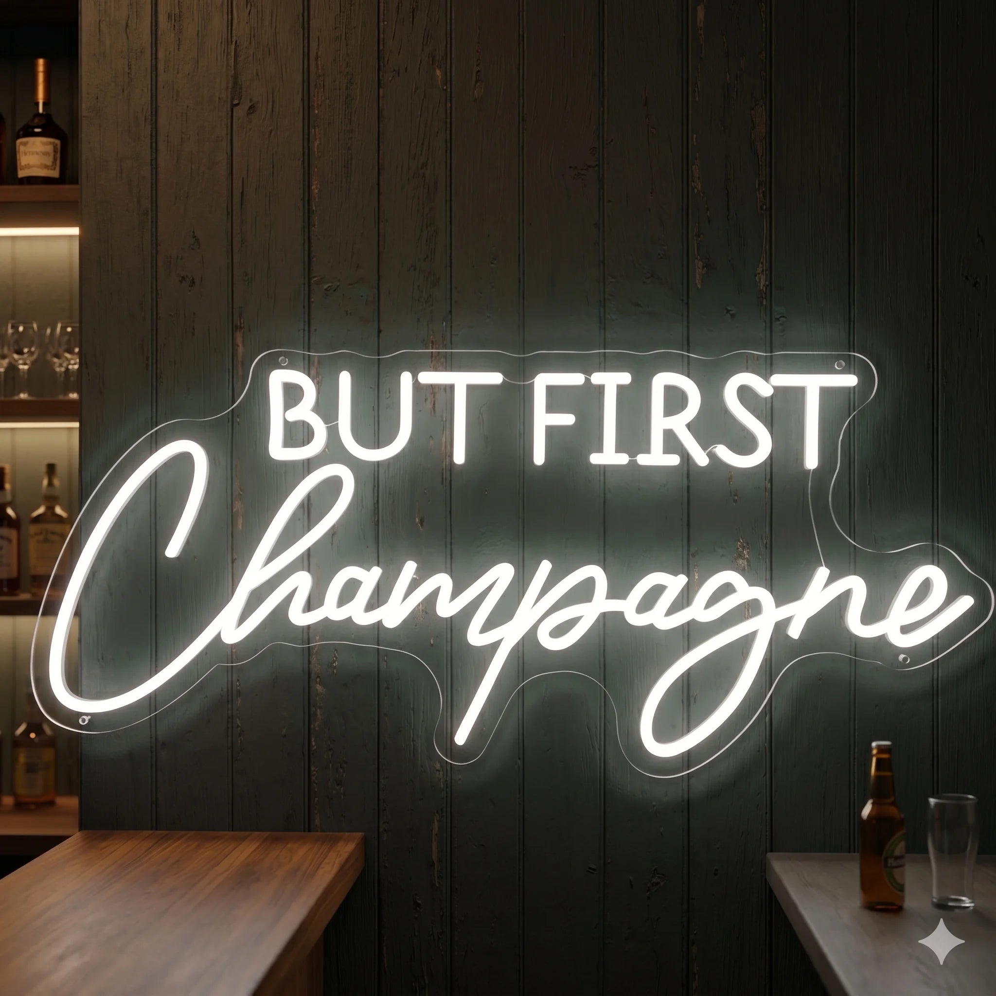 Photo of the 'BUT FIRST CHAMPAGNE' neon sign glowing in cool white against a styled interior wall.