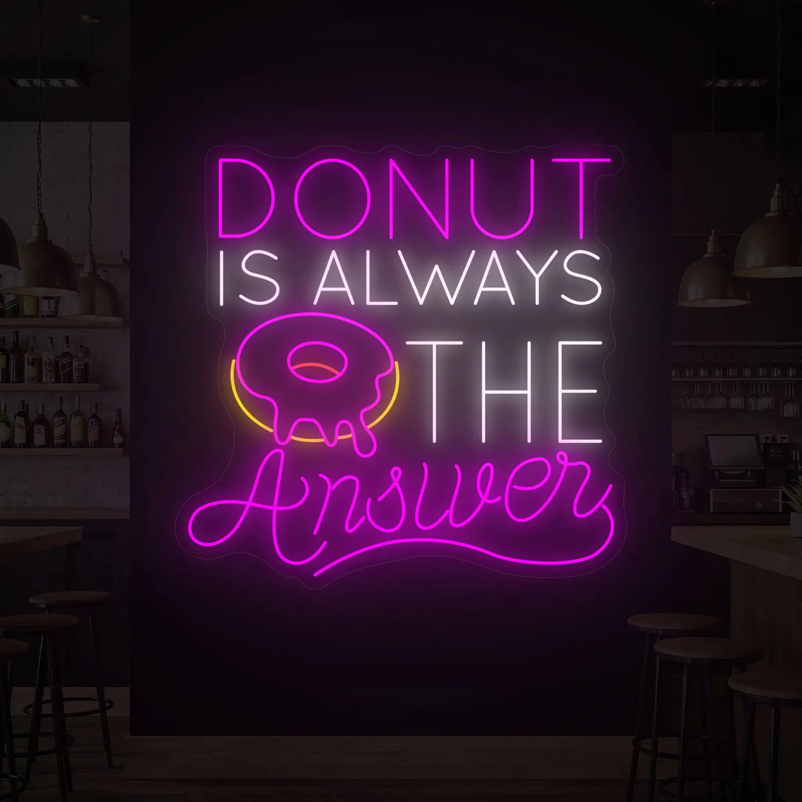 Photo of the 'DONUT IS ALWAYS THE ANSWER' neon sign glowing in multi-color against a styled interior wall.