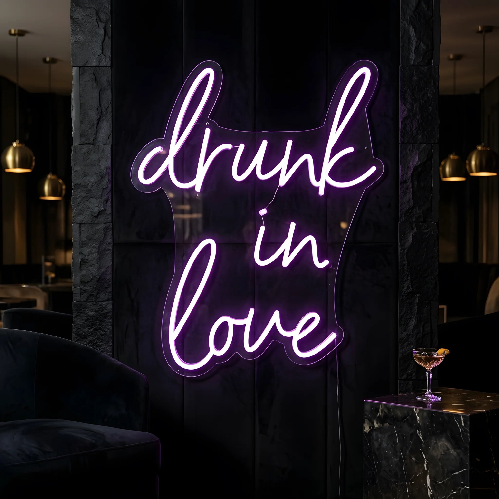 Photo of the 'Drunk in Love' neon sign glowing in purple against a styled interior wall.