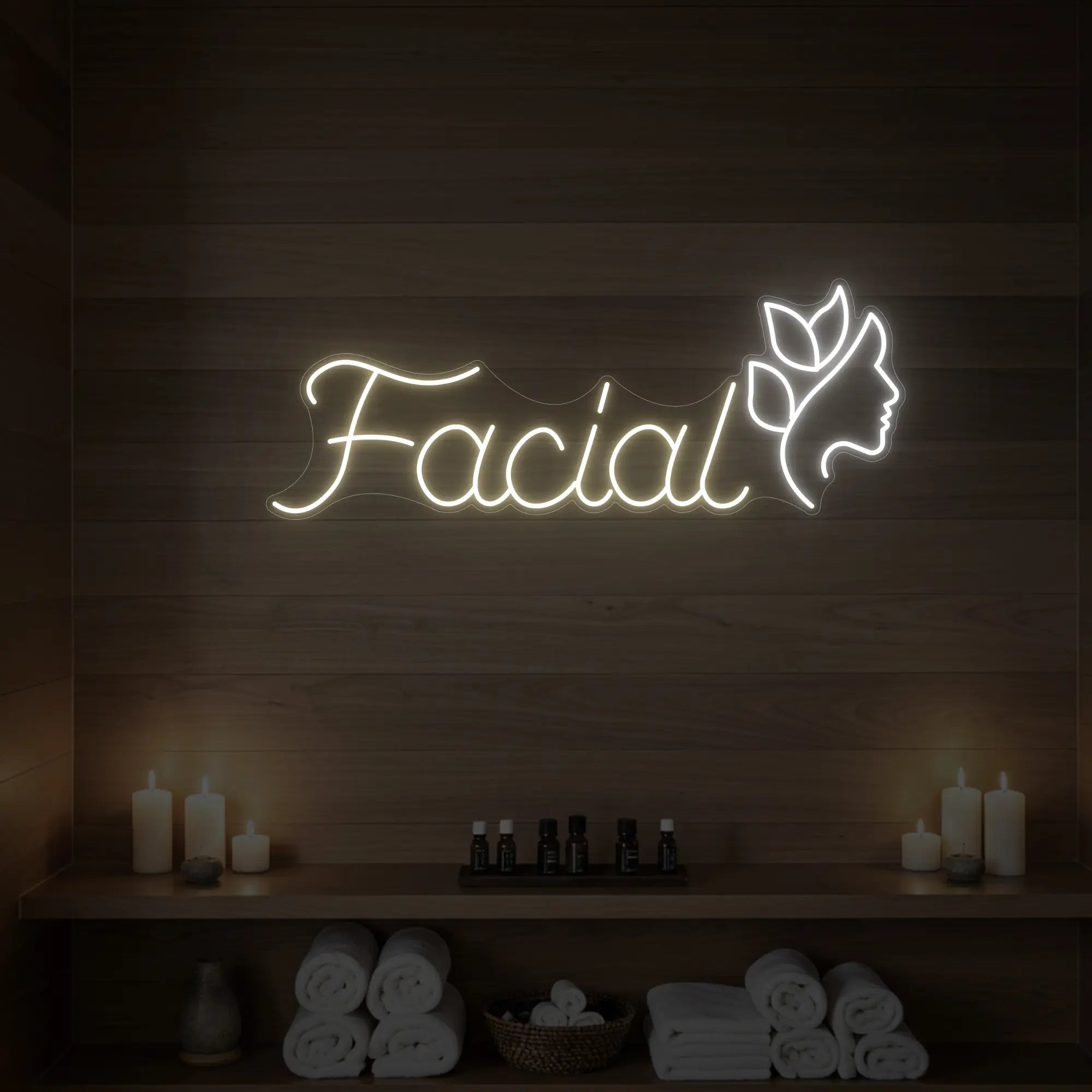 Photo of the 'Facial' neon sign with a botanical face silhouette glowing in warm white against a styled interior wall.