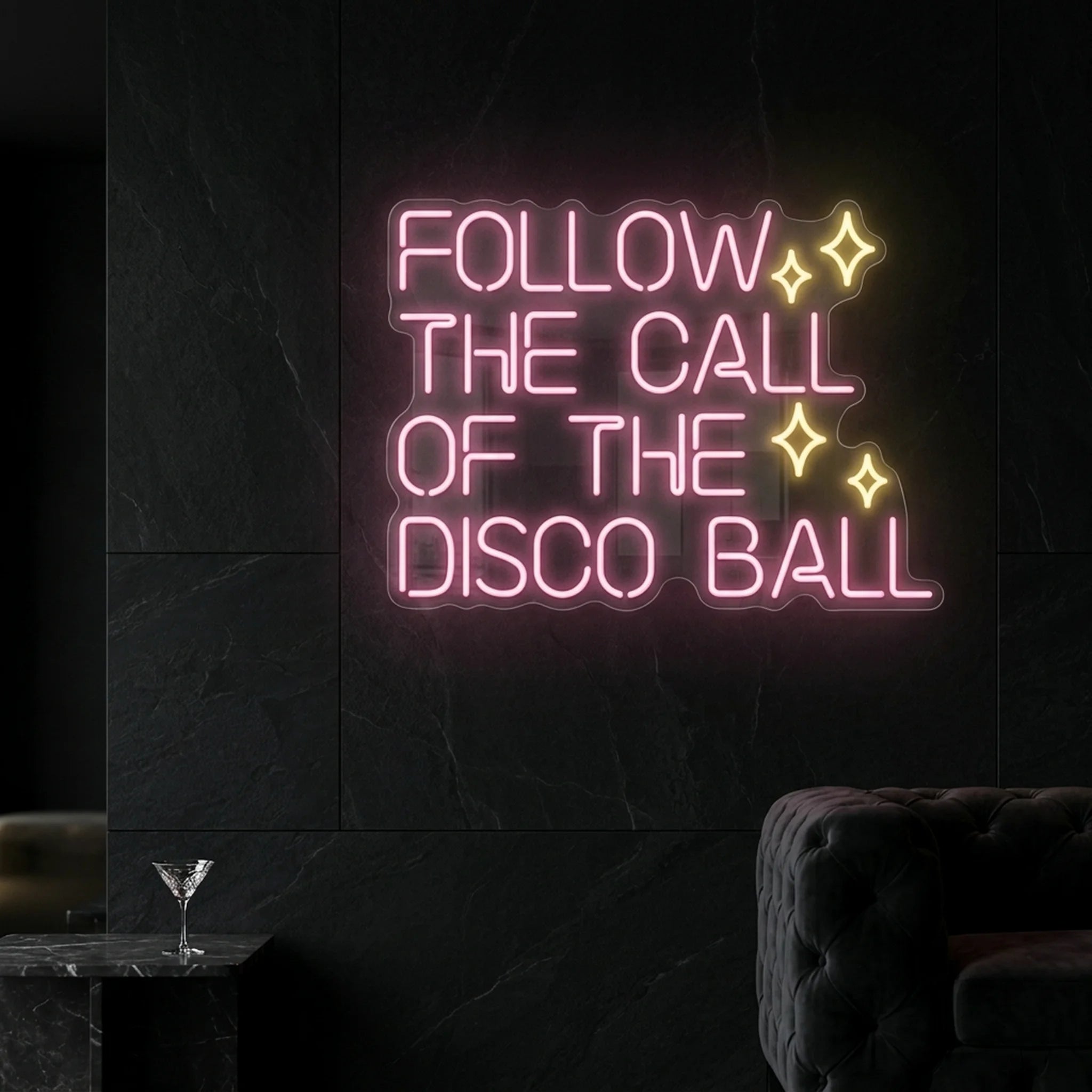 Photo of the 'Follow the Call of the Disco Ball' neon sign glowing in light pink and warm white against a styled interior wall.