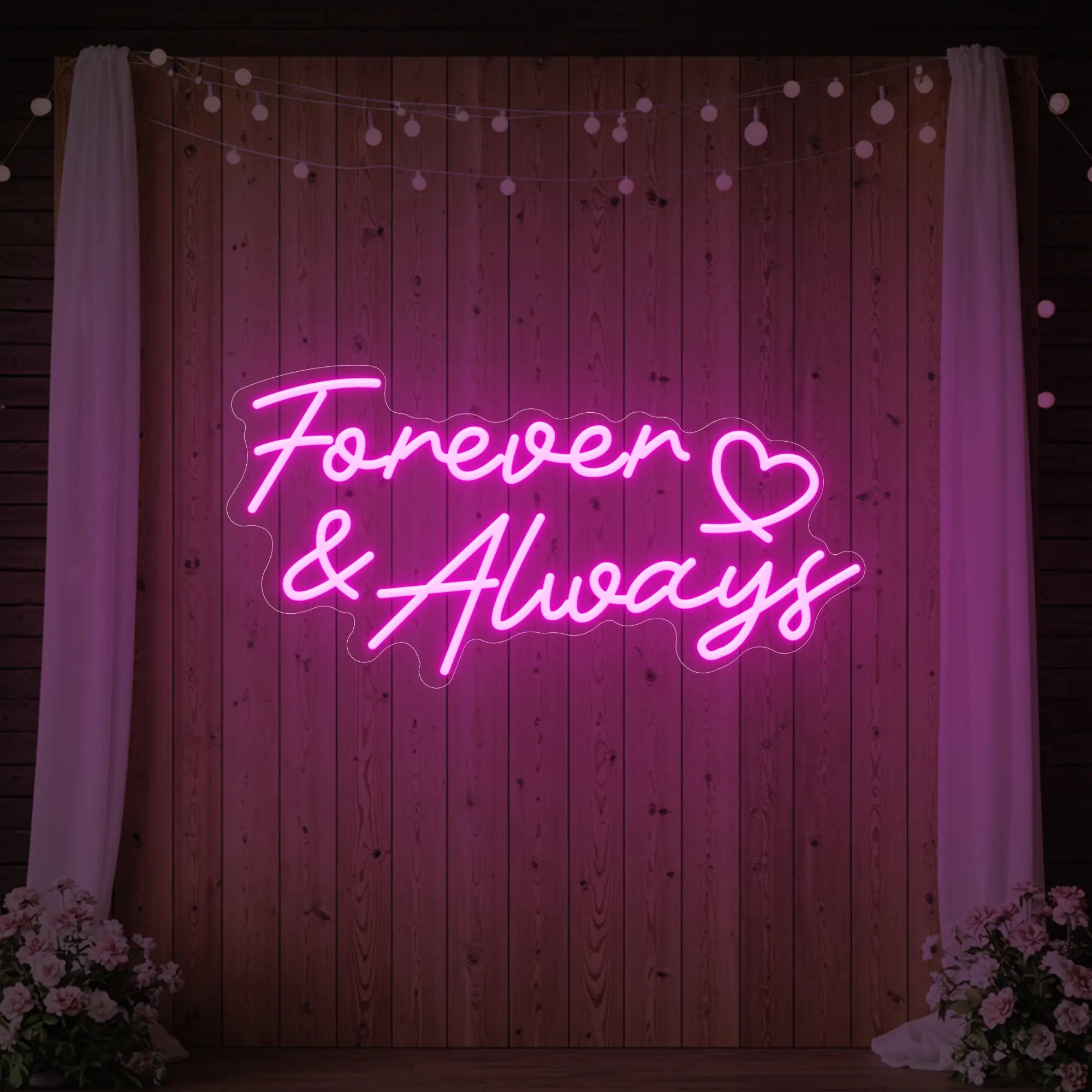 Photo of the 'Forever & Always' neon sign glowing in light pink against a styled interior wall.