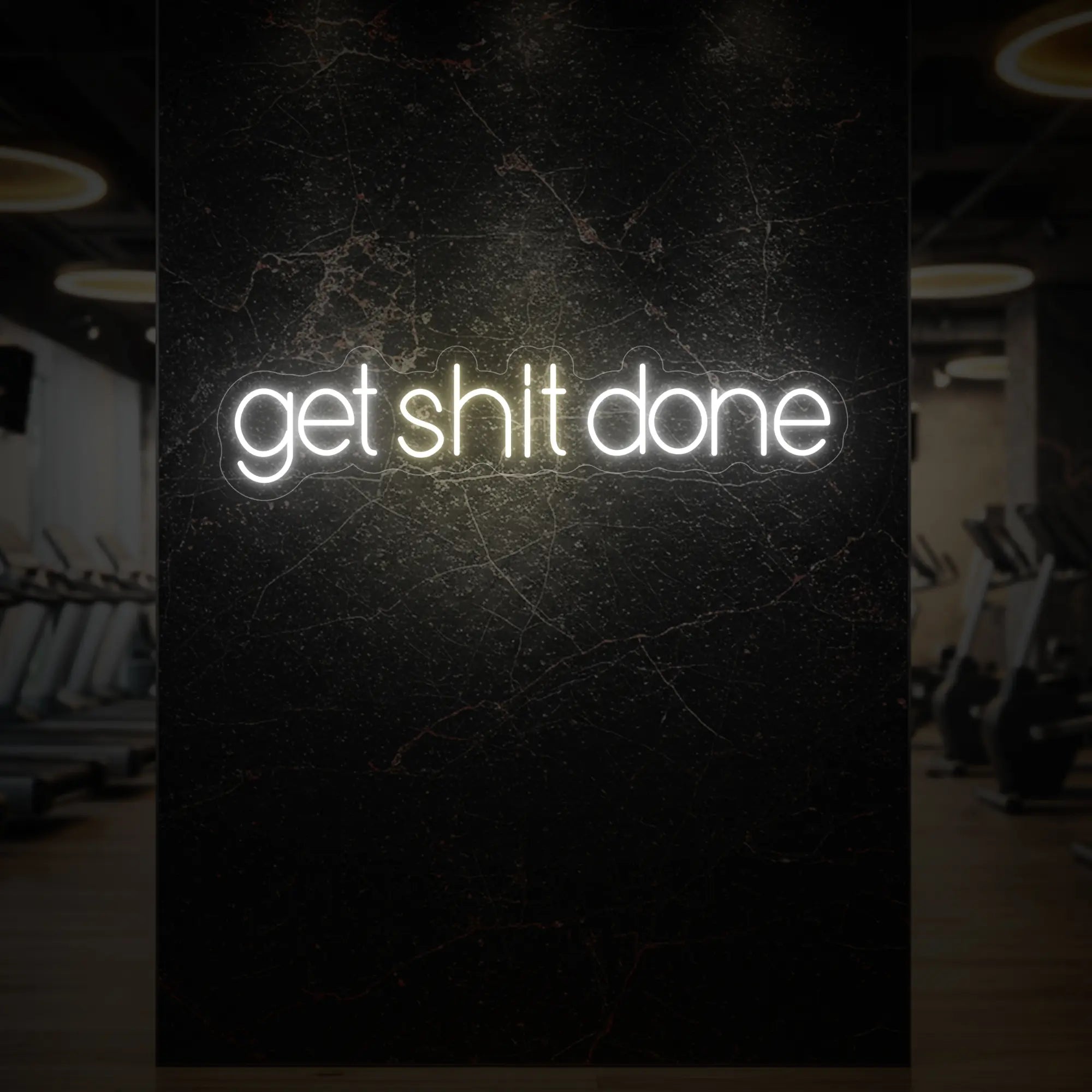 'Get Shit Done' neon sign glowing in warm white against a styled interior wall.