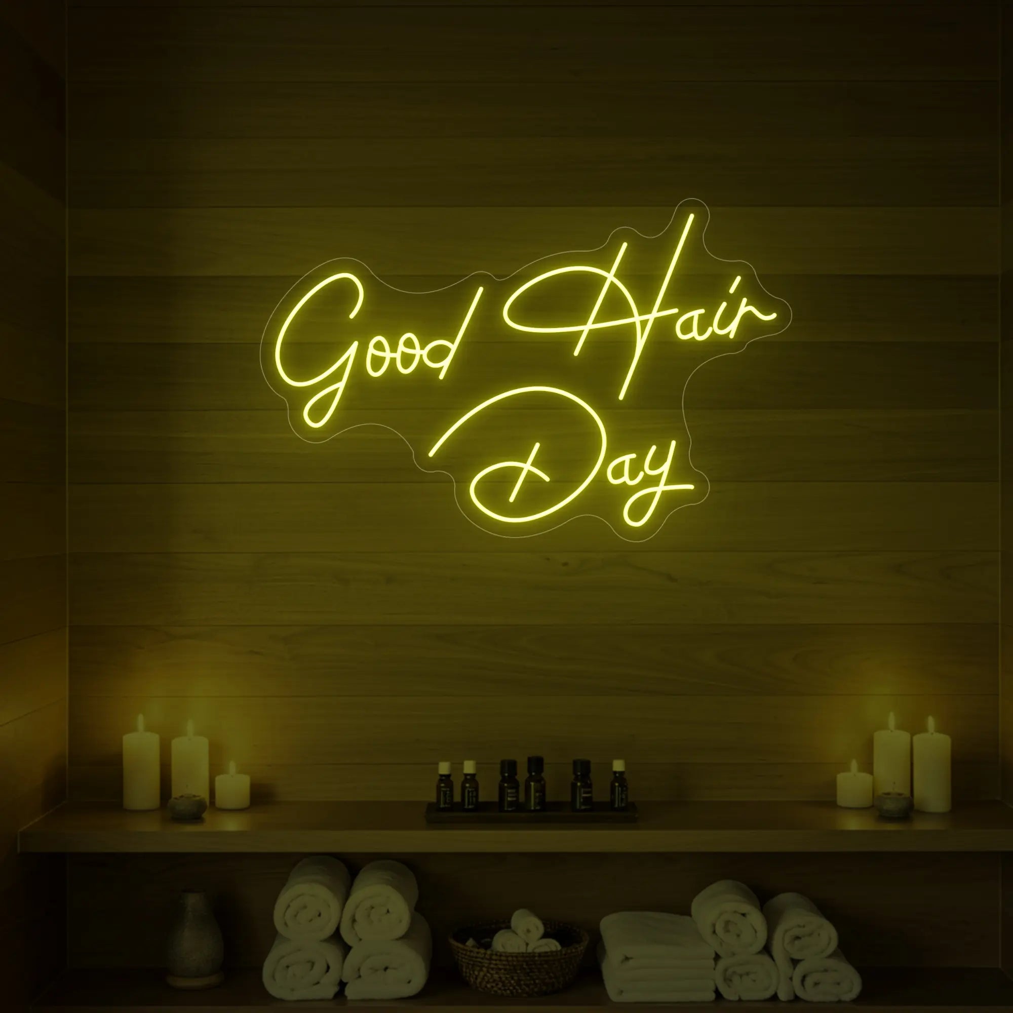 Photo of the 'Good Hair Day' neon sign in cursive glowing in lemon yellow against a styled interior wall.