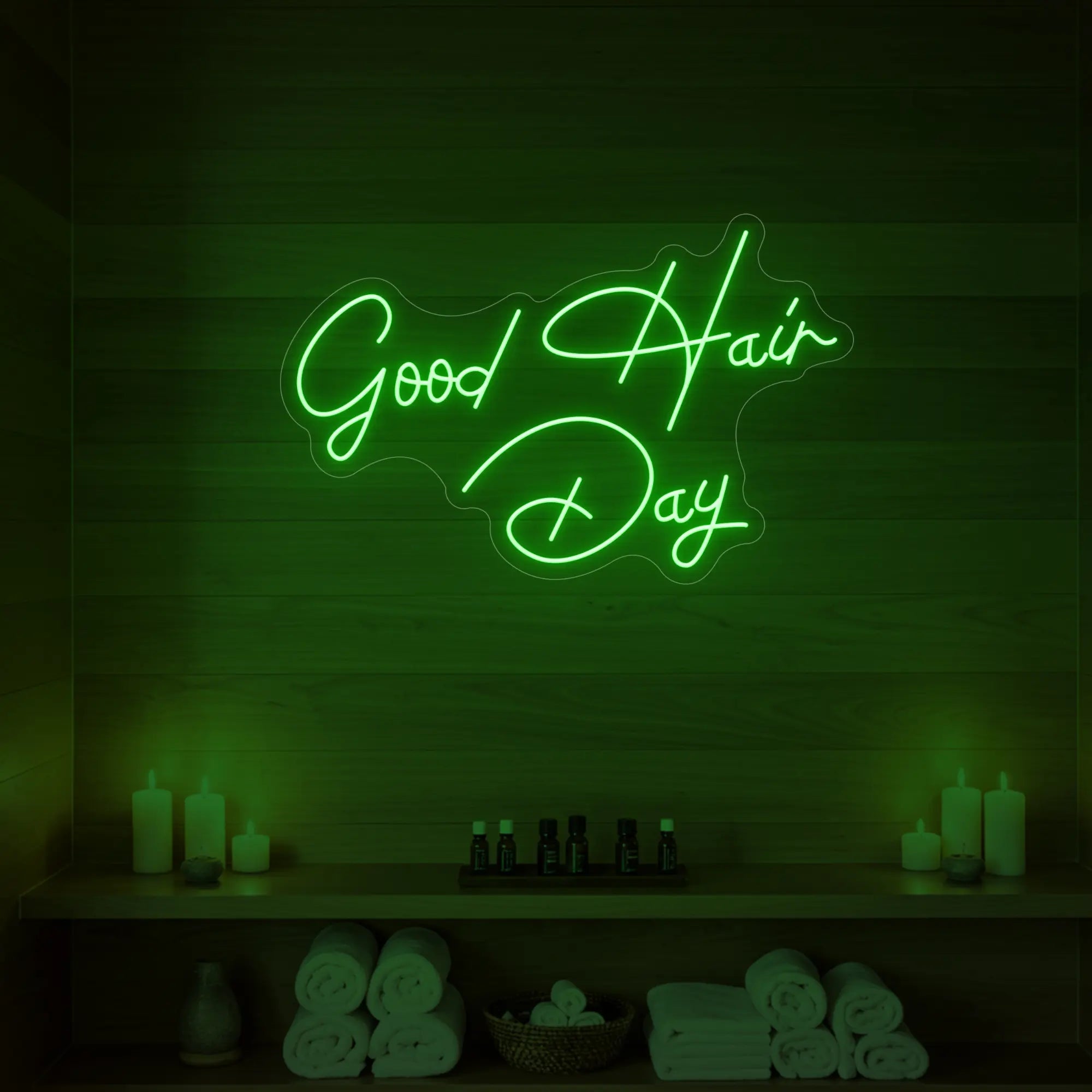 Photo of the 'Good Hair Day' neon sign in cursive glowing in green against a styled interior wall.