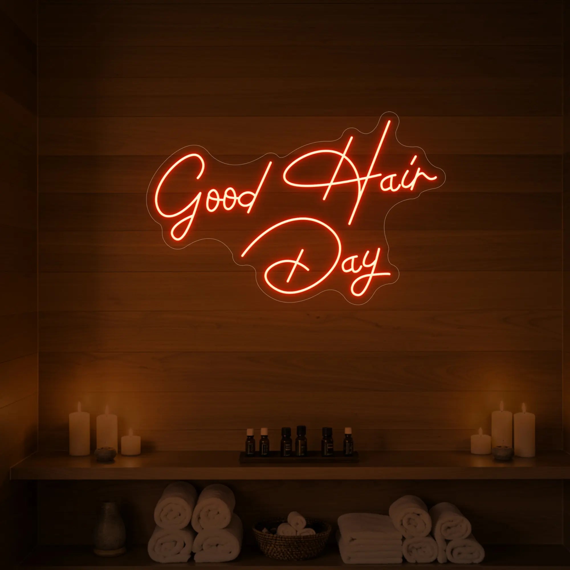 Photo of the 'Good Hair Day' neon sign in cursive glowing in golden yellow against a styled interior wall.