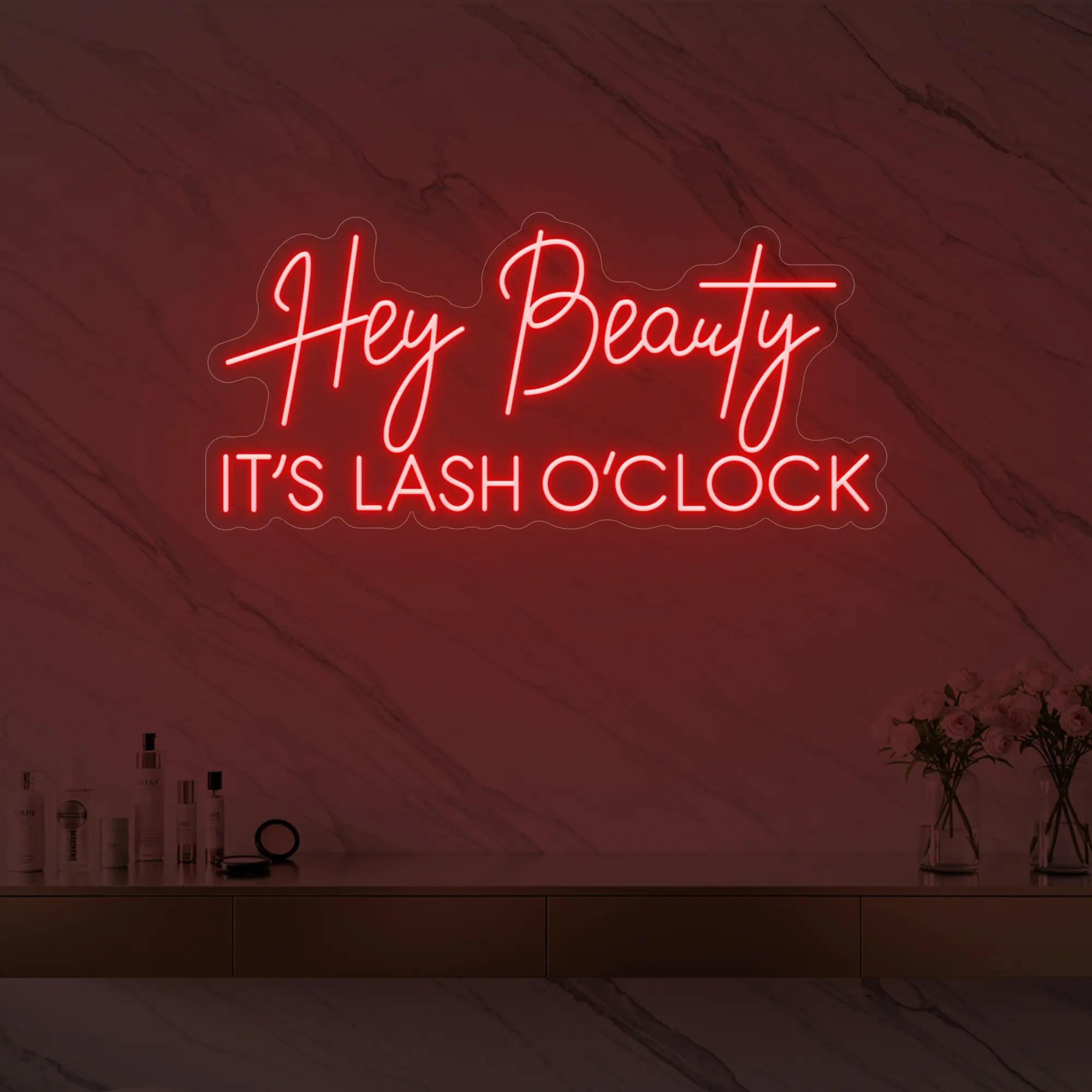 Photo of the 'Hey Beauty IT’S LASH O’CLOCK' neon sign glowing in red against a styled interior wall.