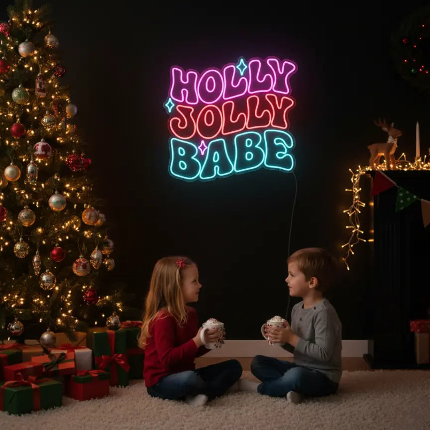 Photo of the 'Holly Jolly Babe' neon sign glowing in multicolor against a styled interior wall.
