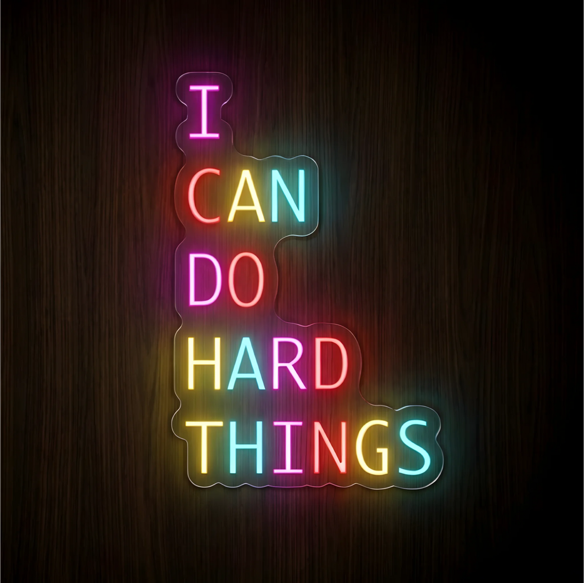“I CAN DO HARD THINGS” LED Neon Sign with multicolor pink, red, yellow, and cyan lettering on clear acrylic backing against a dark wood background, suited to home offices, study areas, and fitness spaces.