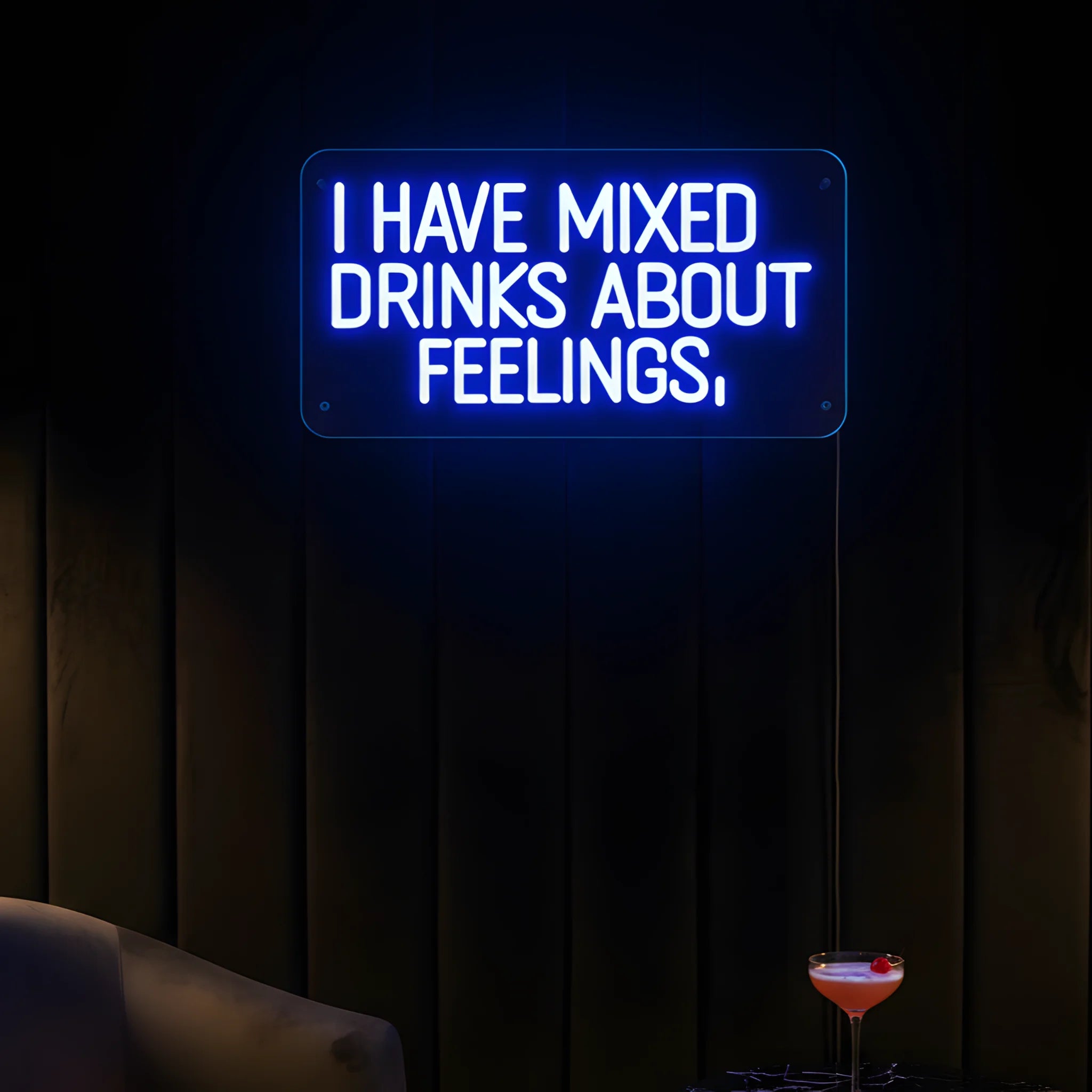 Photo of the 'I Have Mixed Drinks About Feelings' neon sign glowing in blue against a styled interior wall.