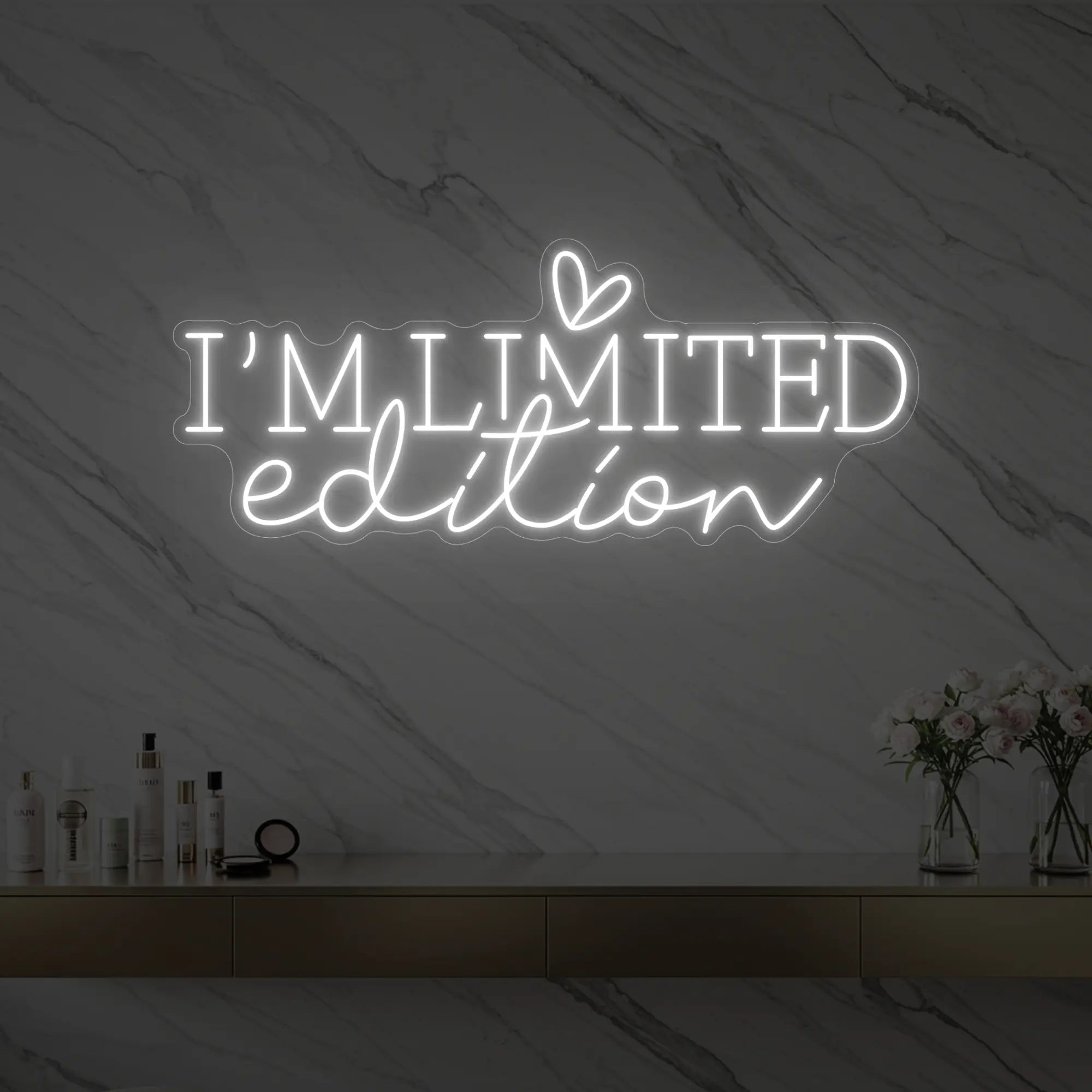 Photo of the 'I’M LIMITED edition' neon sign with a heart icon glowing in cool white against a styled interior wall.