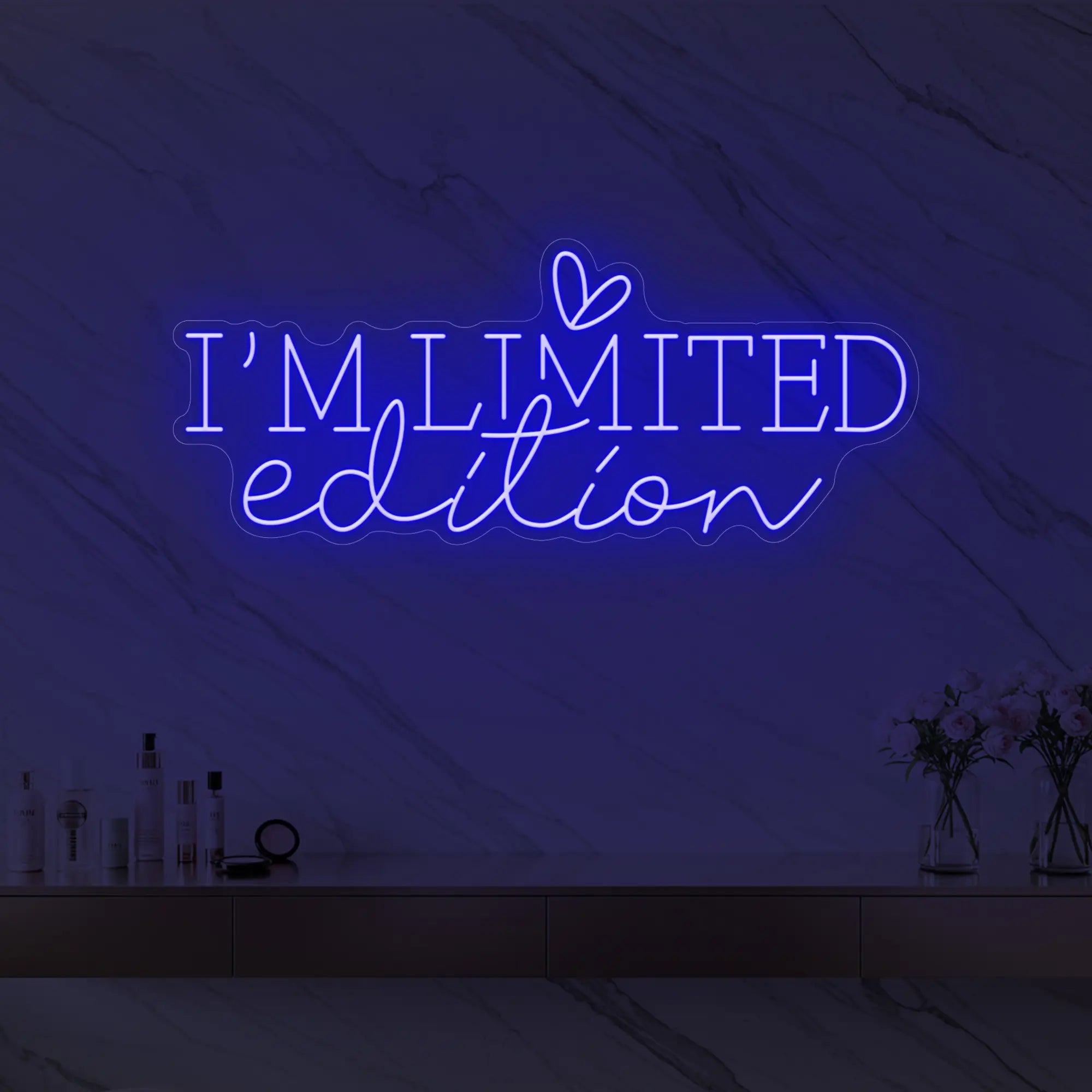 Photo of the 'I’M LIMITED edition' neon sign with a heart icon glowing in deep blue against a styled interior wall.