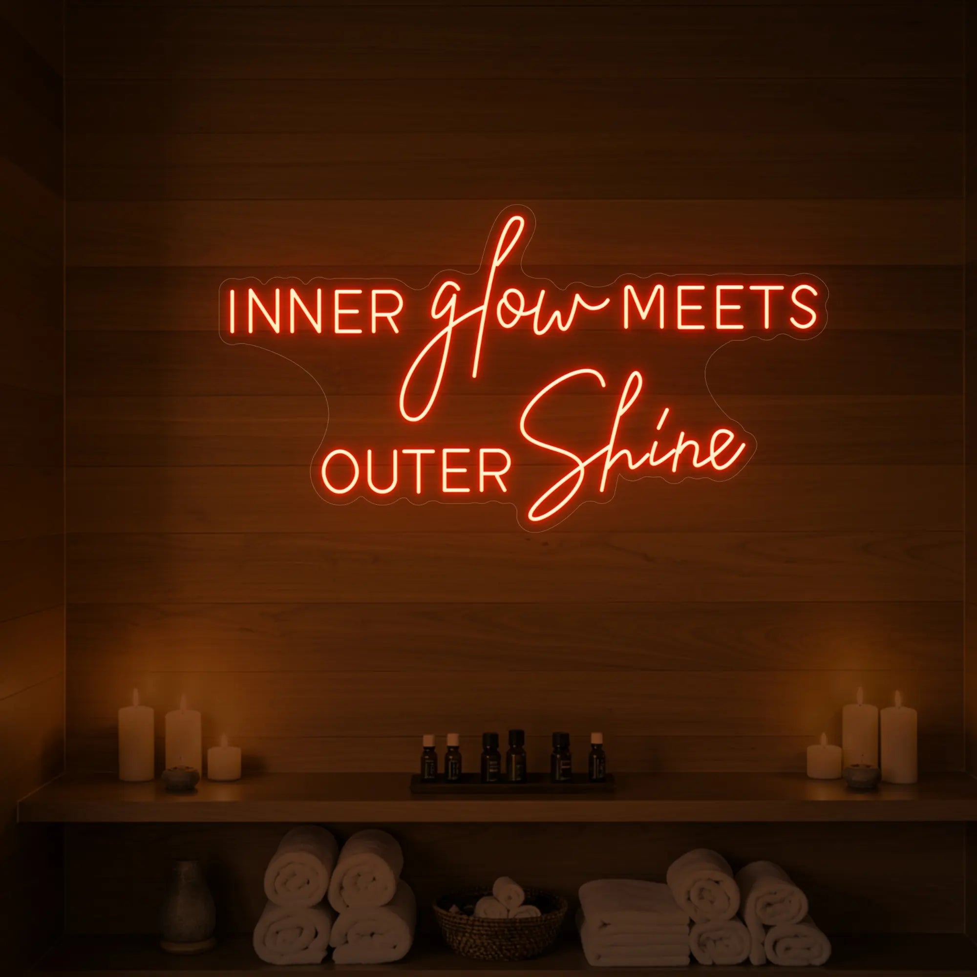 Photo of the 'INNER glow MEETS OUTER Shine' neon sign glowing in golden yellow against a styled interior wall.