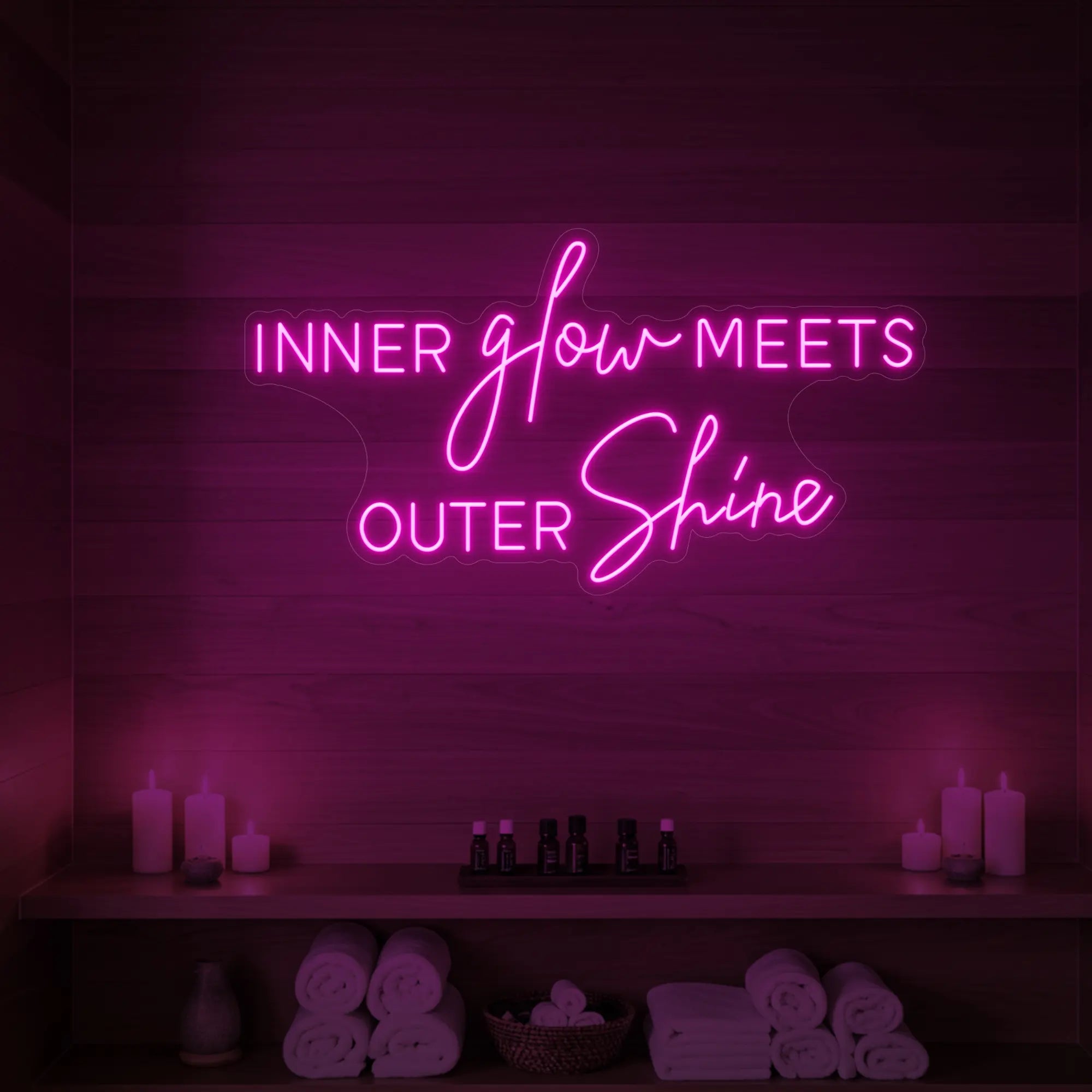 Photo of the 'INNER glow MEETS OUTER Shine' neon sign glowing in light pink against a styled interior wall.