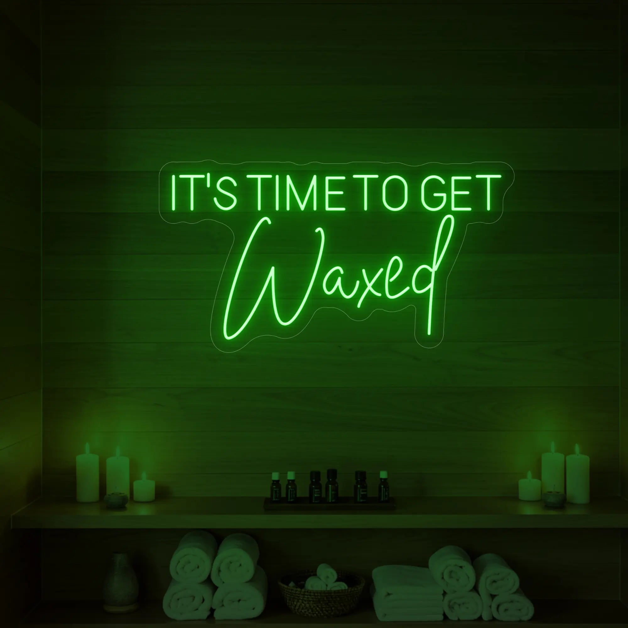 Photo of the 'IT’S TIME TO GET Waxed' neon sign glowing in green against a styled interior wall.