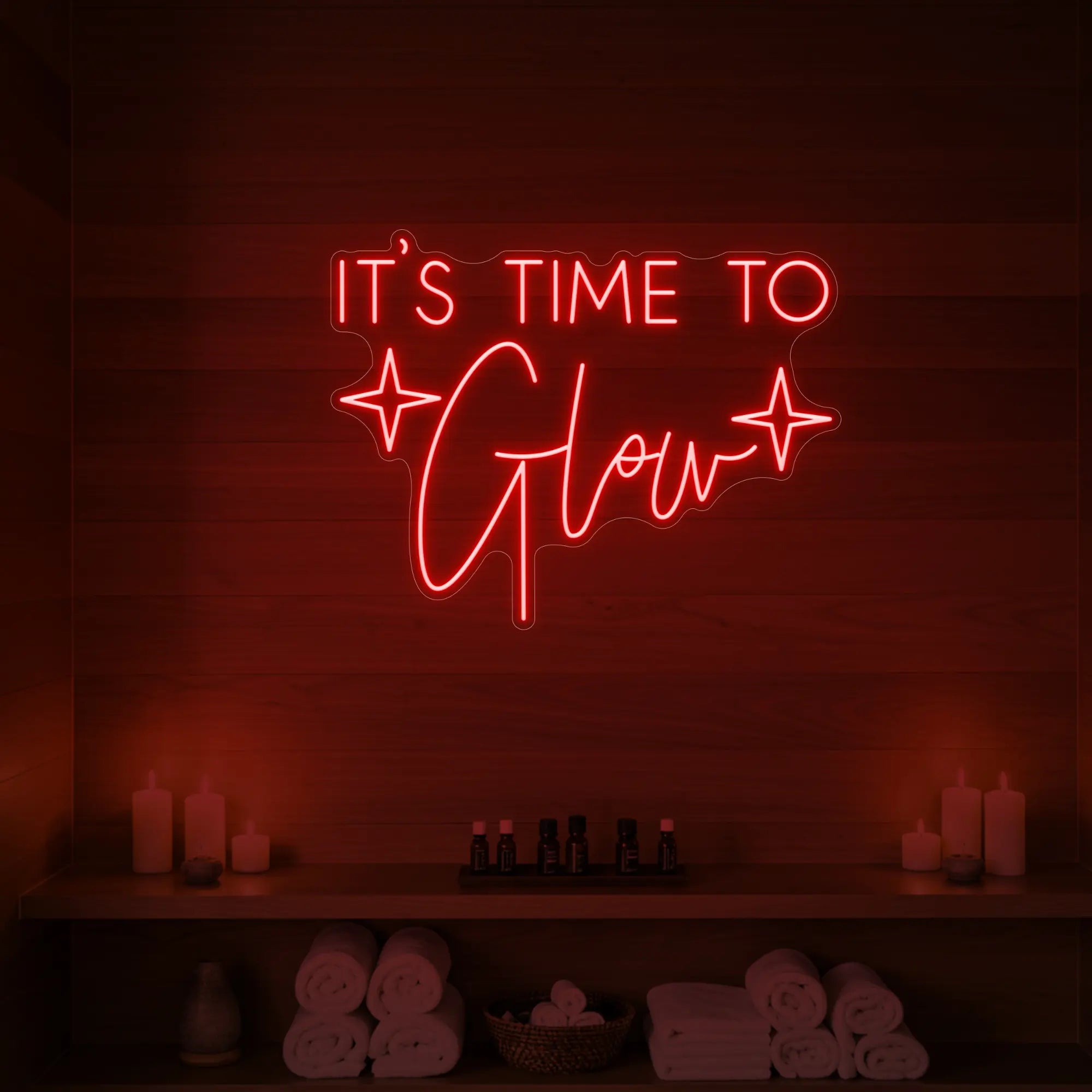 Photo of the 'IT’S TIME TO Glow' neon sign with sparkle icons glowing in red against a styled interior wall.