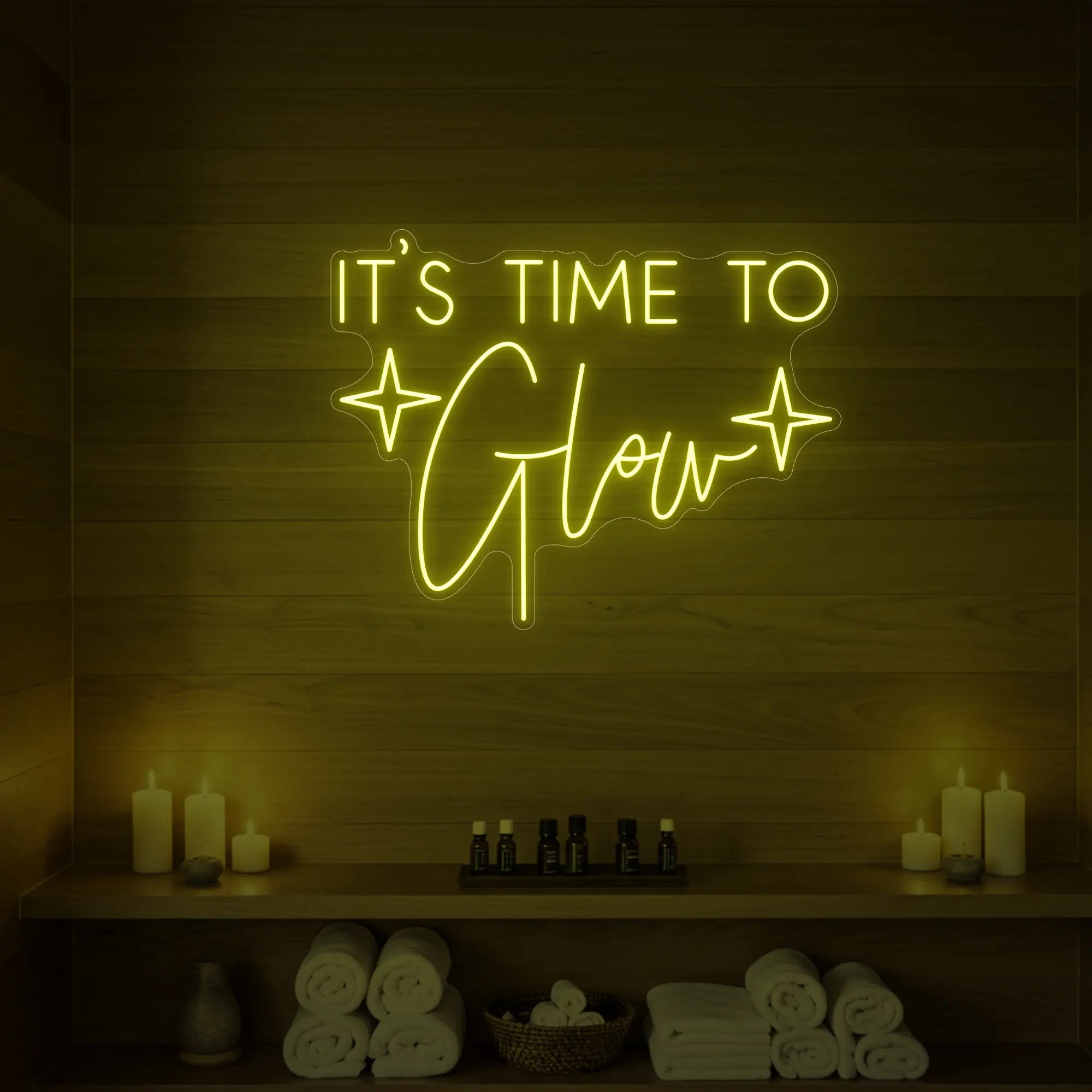 Photo of the 'IT’S TIME TO Glow' neon sign with sparkle icons glowing in lemon yellow against a styled interior wall.