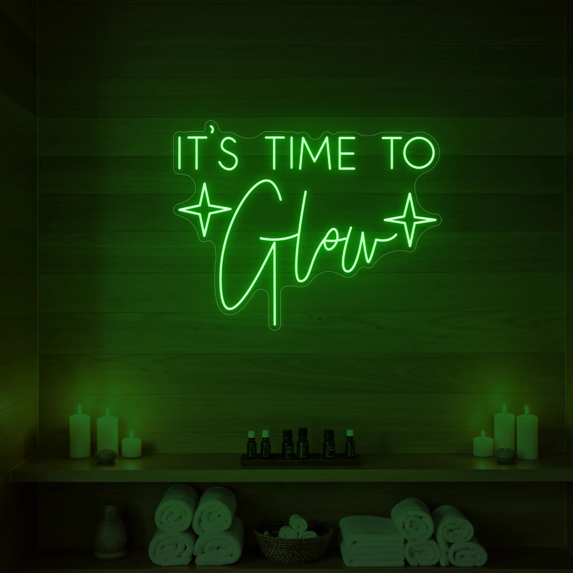 Photo of the 'IT’S TIME TO Glow' neon sign with sparkle icons glowing in green against a styled interior wall.