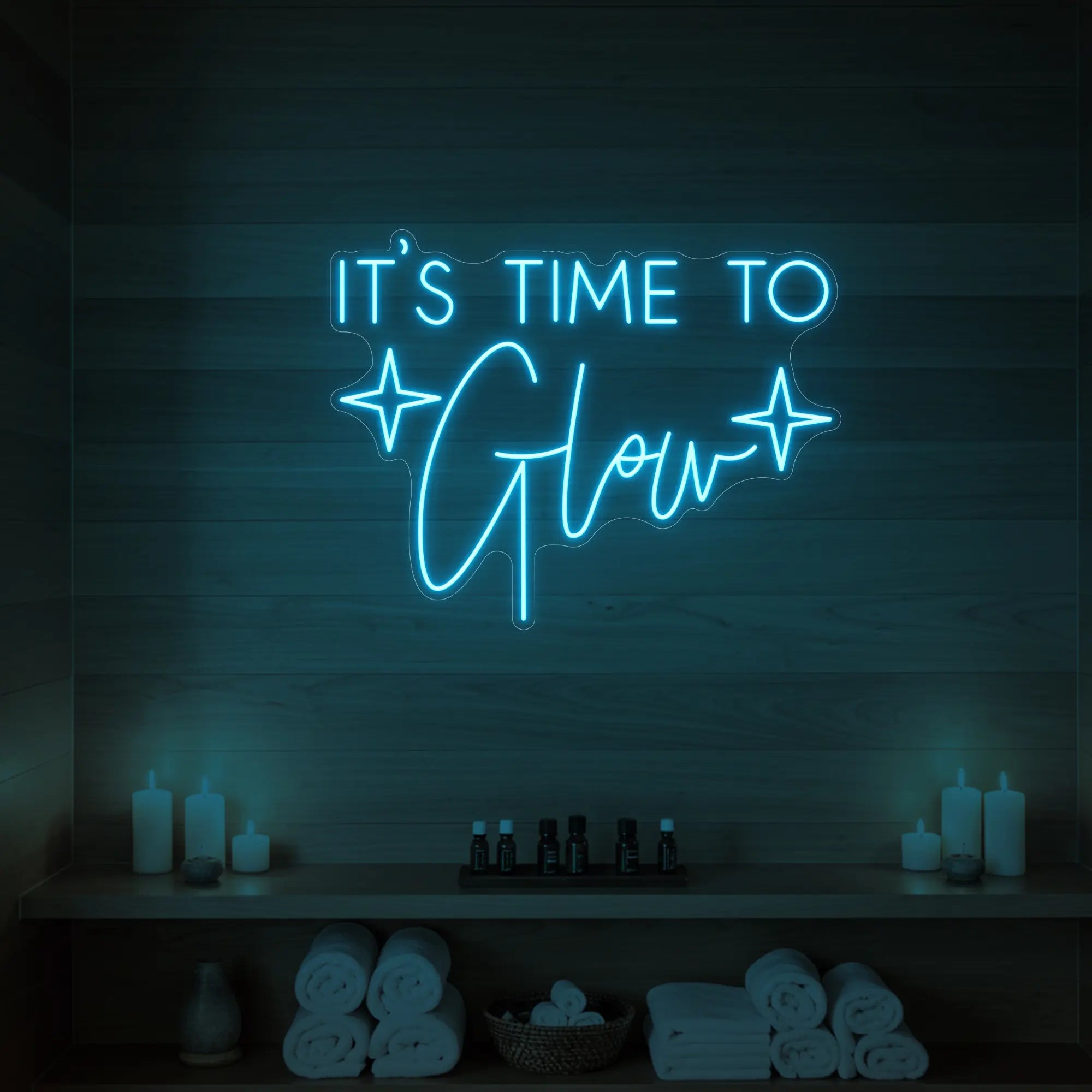 Photo of the 'IT’S TIME TO Glow' neon sign with sparkle icons glowing in ice blue against a styled interior wall.
