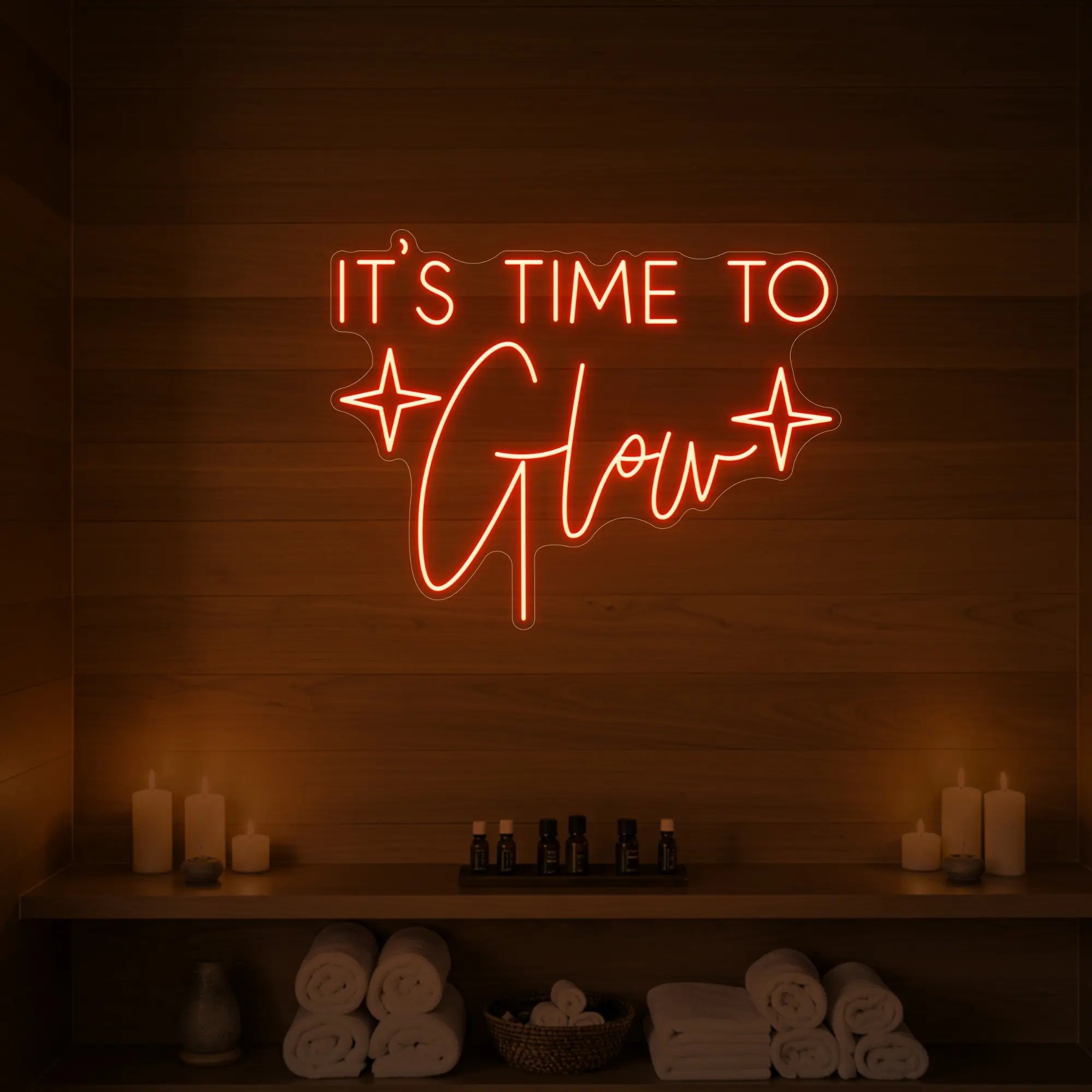 Photo of the 'IT’S TIME TO Glow' neon sign with sparkle icons glowing in golden yellow against a styled interior wall.