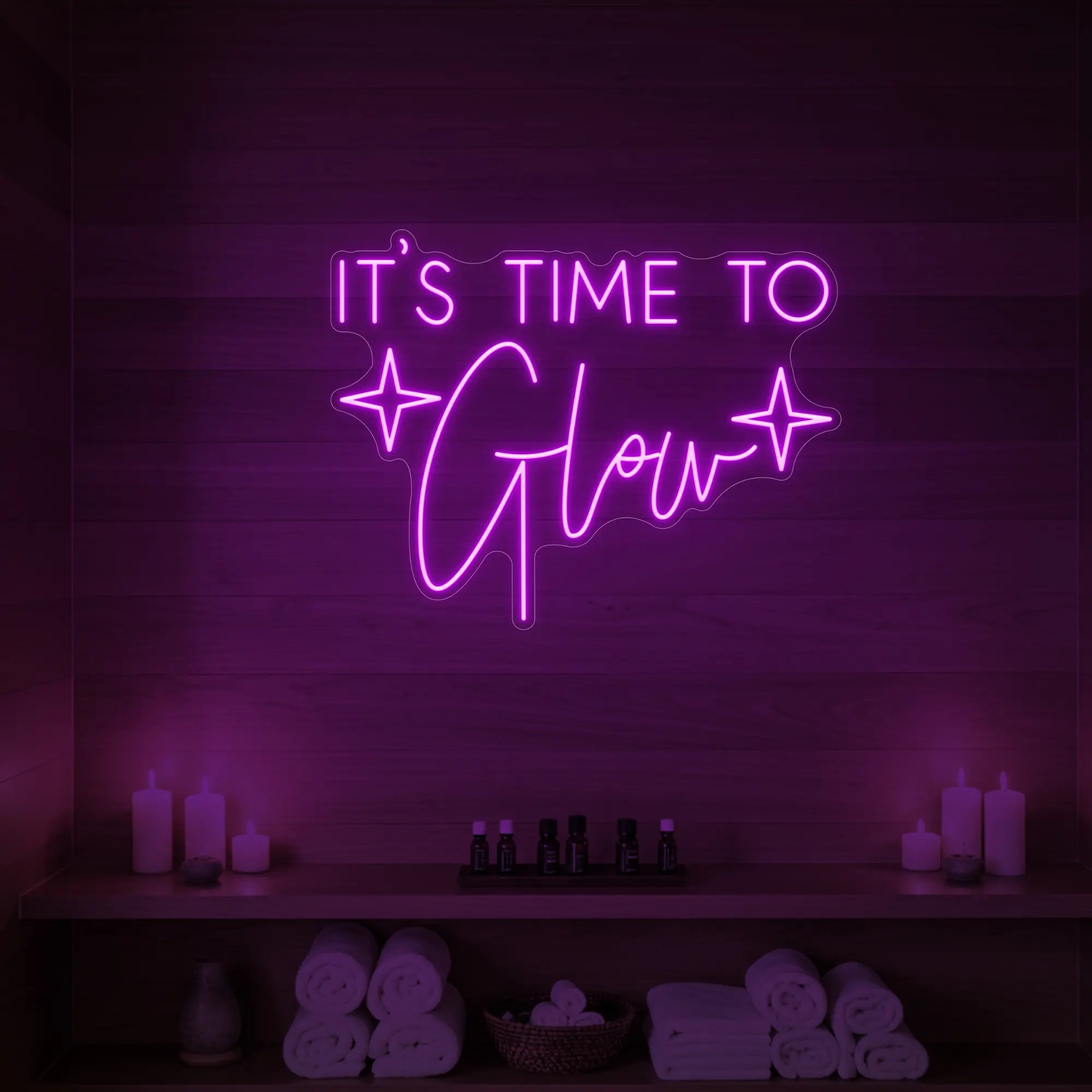 Photo of the 'IT’S TIME TO Glow' neon sign with sparkle icons glowing in deep pink against a styled interior wall.