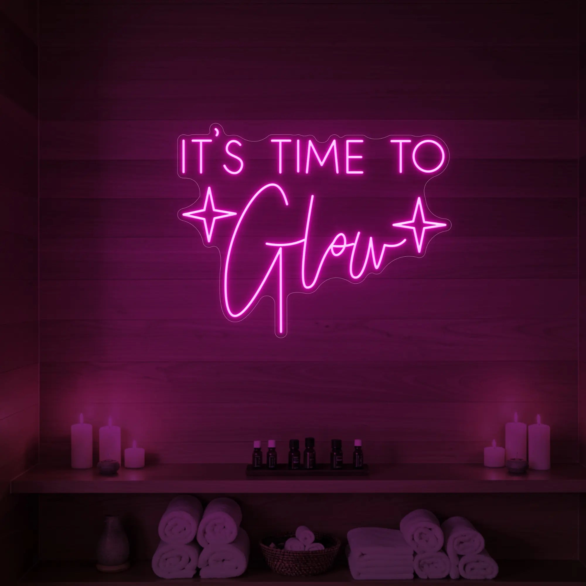 Photo of the 'IT’S TIME TO Glow' neon sign with sparkle icons glowing in light pink against a styled interior wall.