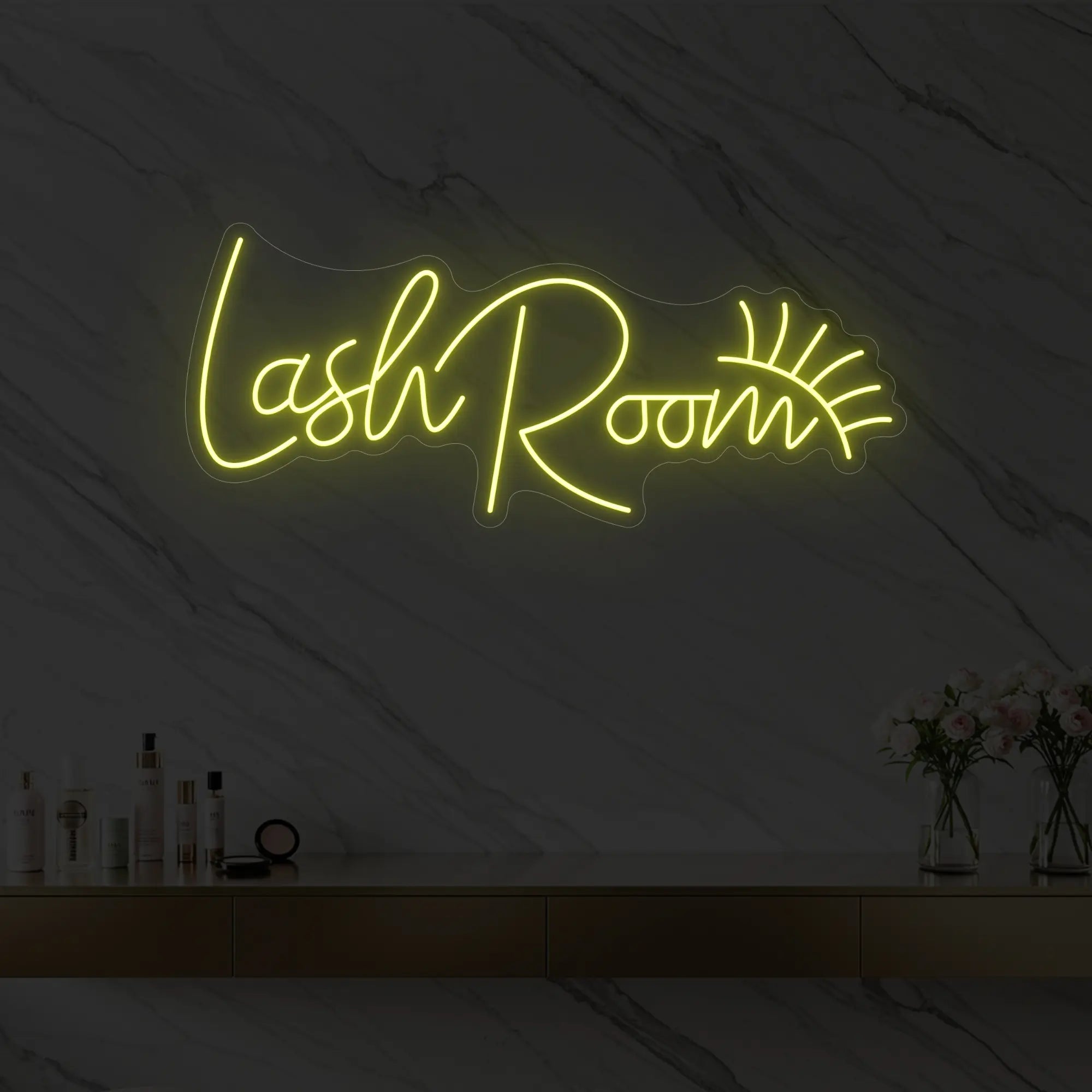 Photo of the 'Lash Room' neon sign with an eyelash icon glowing in lemon yellow against a styled interior wall.