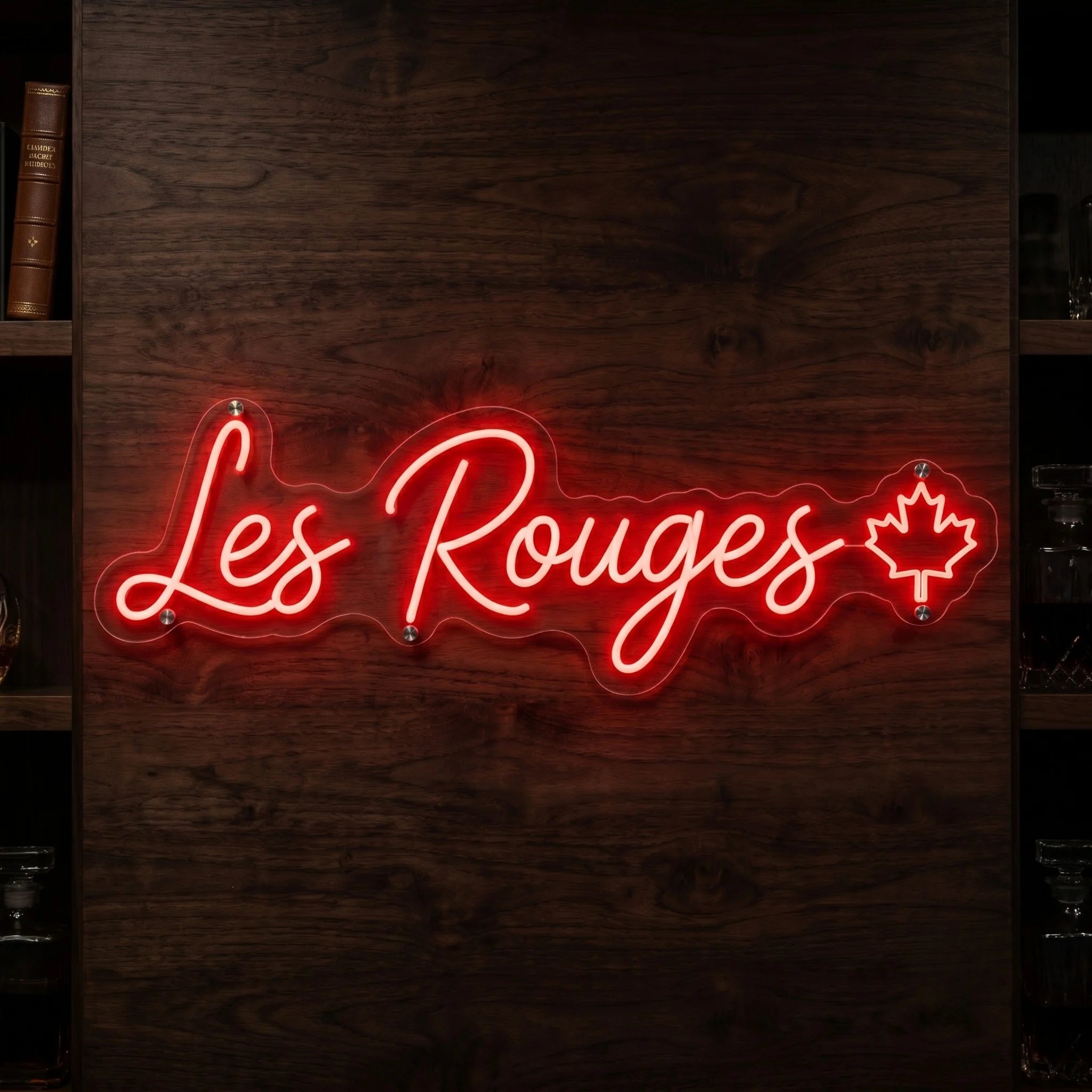 Les Rouges LED neon sign in bright red script lettering with maple leaf accent mounted on clear acrylic backing