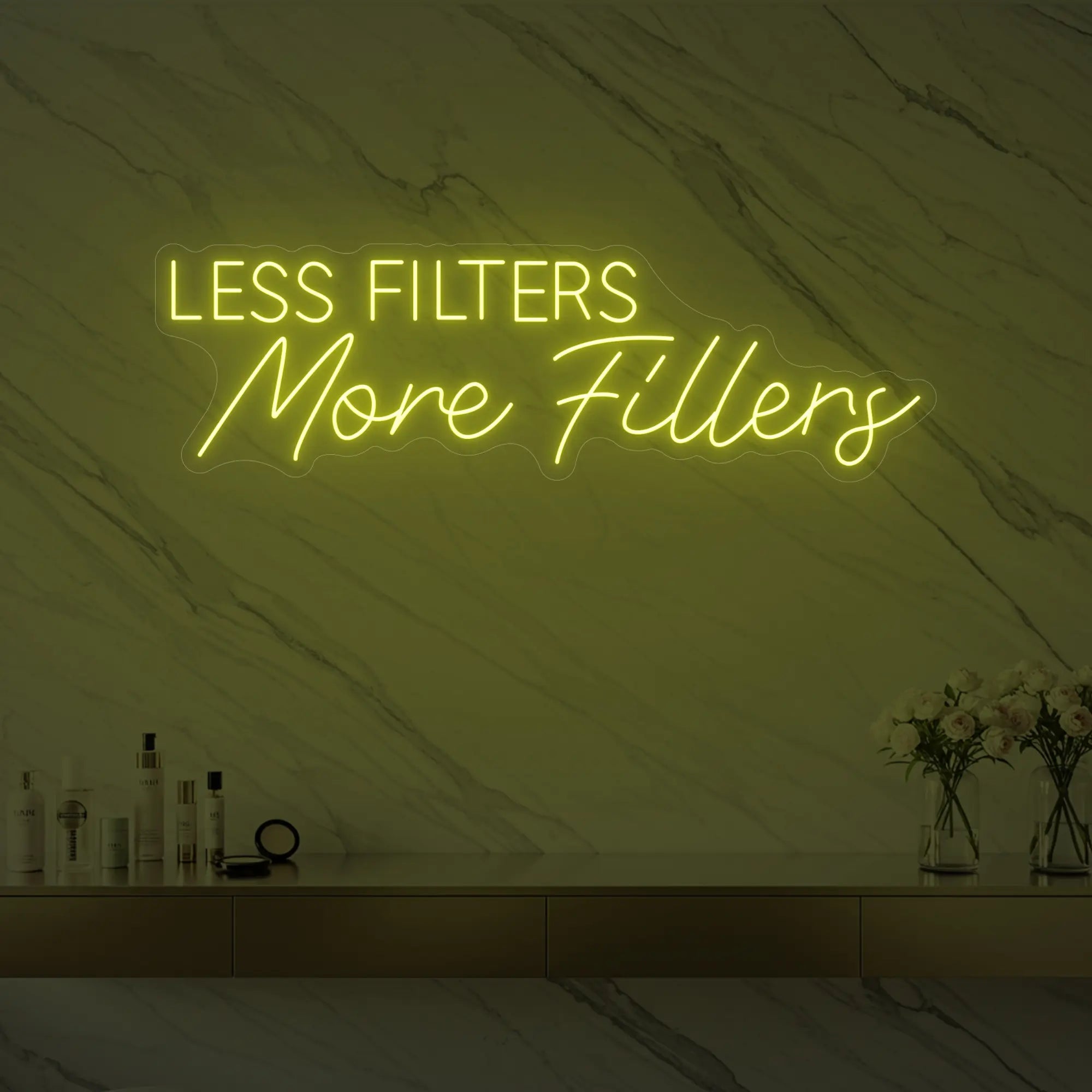 Photo of the 'LESS FILTERS MORE FILLERS' neon sign glowing in lemon yellow against a marble wall.