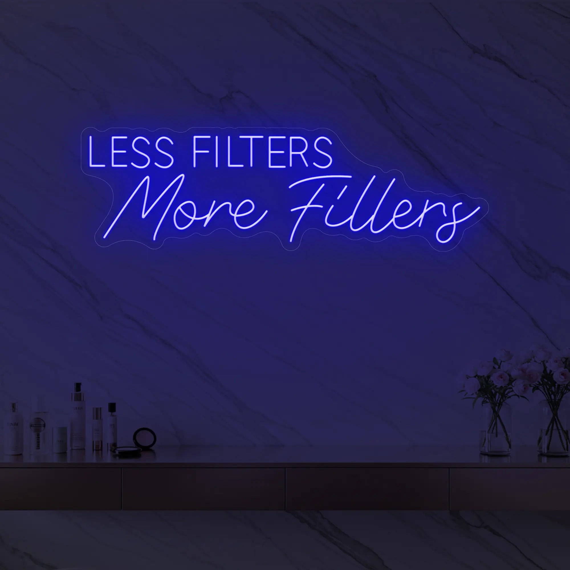 Photo of the 'LESS FILTERS MORE FILLERS' neon sign glowing in deep blue against a marble wall.
