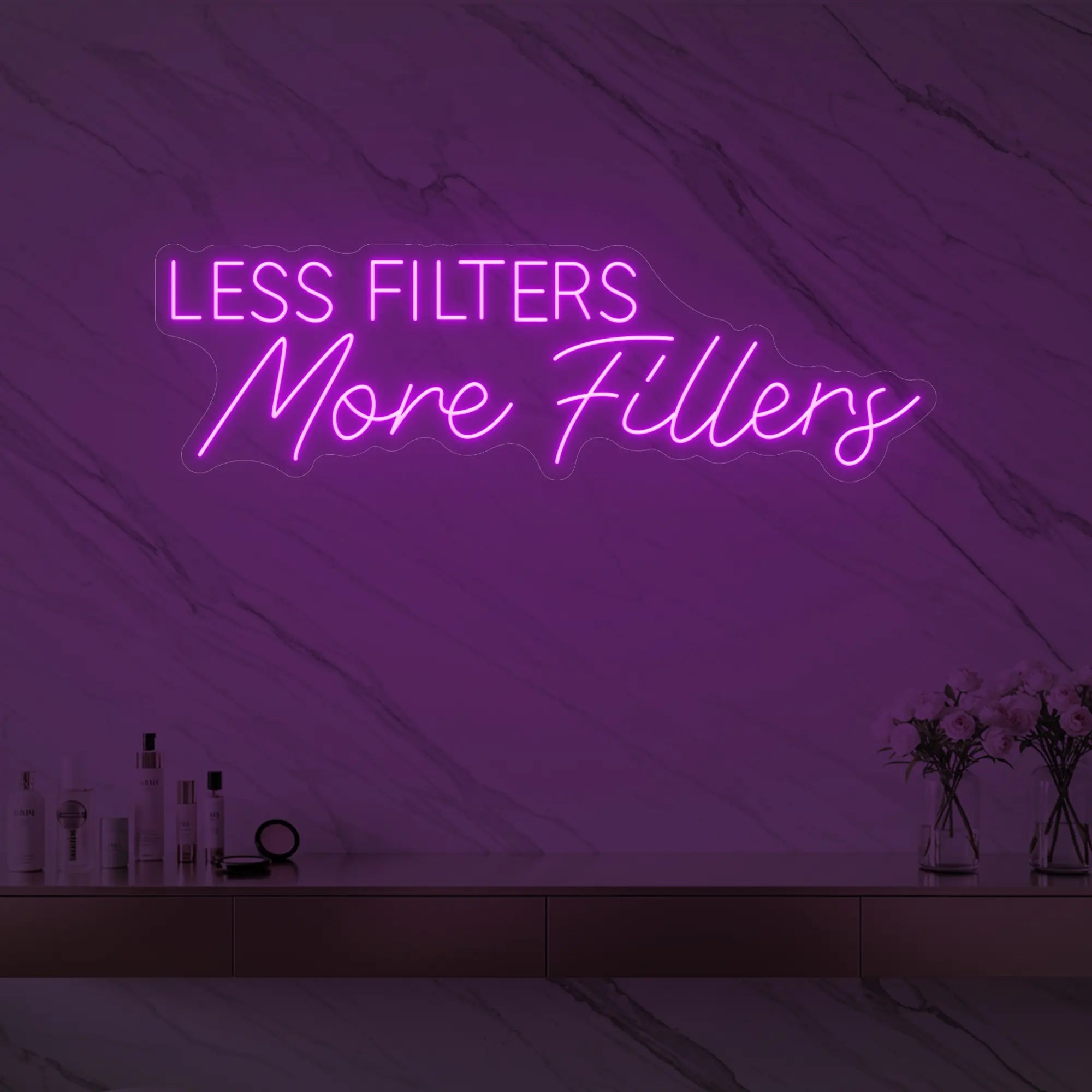 Photo of the 'LESS FILTERS MORE FILLERS' neon sign glowing in deep pink against a marble wall.