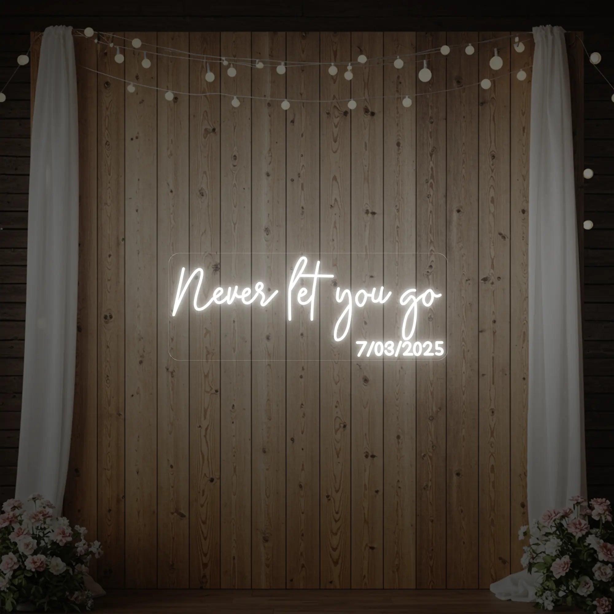 'Never Let You Go' neon sign glowing in cool white against a styled interior wall.