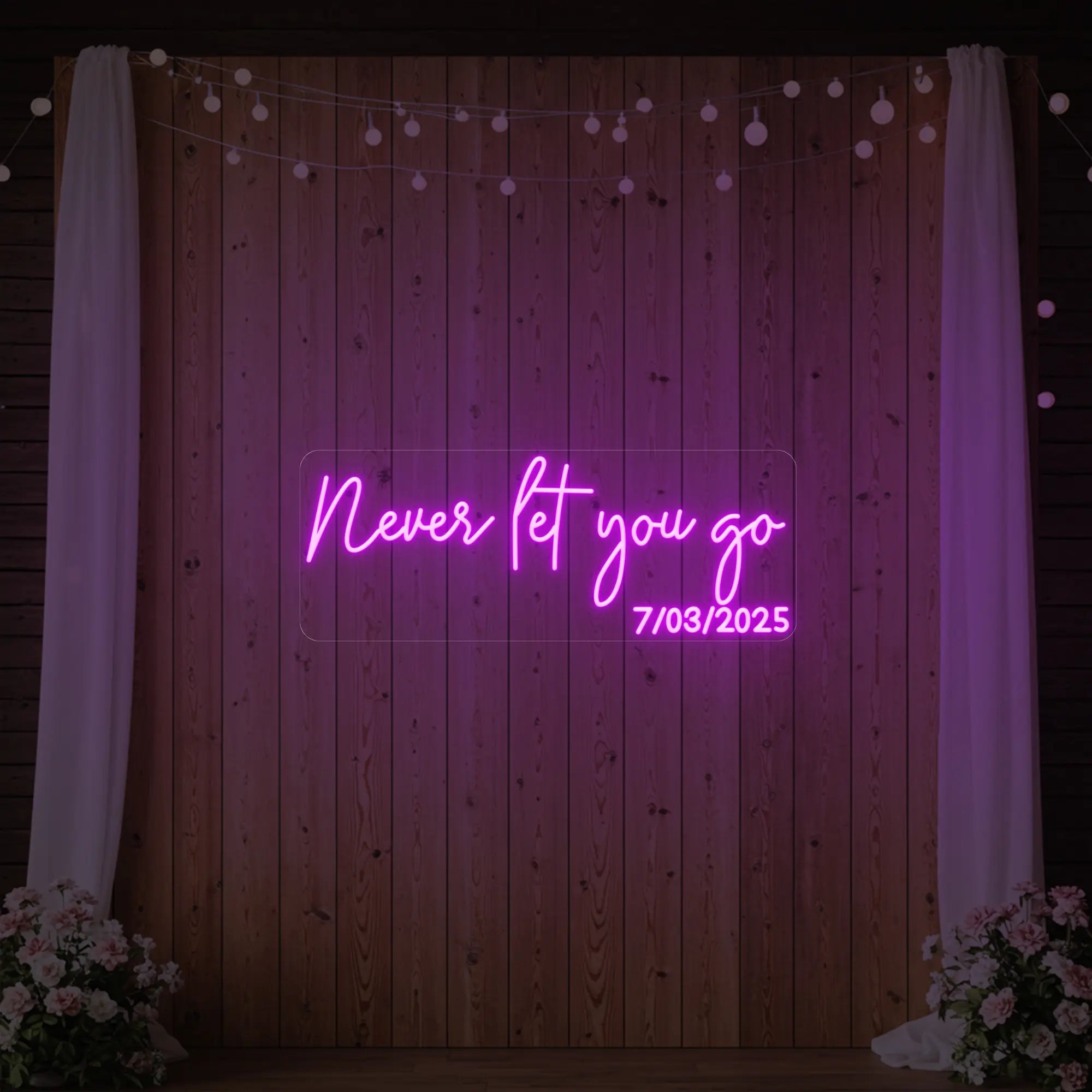 'Never Let You Go' neon sign glowing in light pink against a styled interior wall.