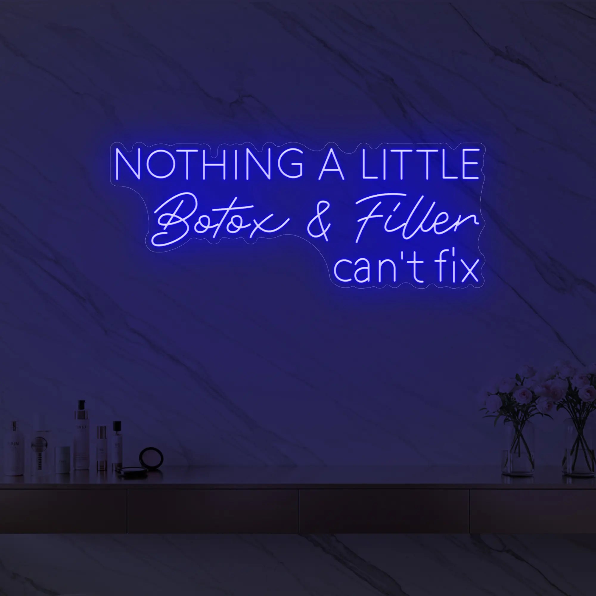 Photo of the 'Nothing a Little Botox & Filler Can’t Fix' neon sign glowing in deep blue against a styled interior wall.