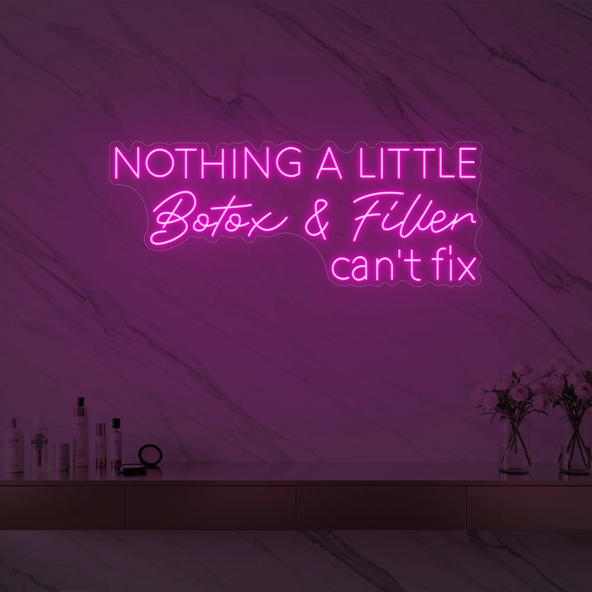 Photo of the 'Nothing a Little Botox & Filler Can’t Fix' neon sign glowing in light pink against a styled interior wall.