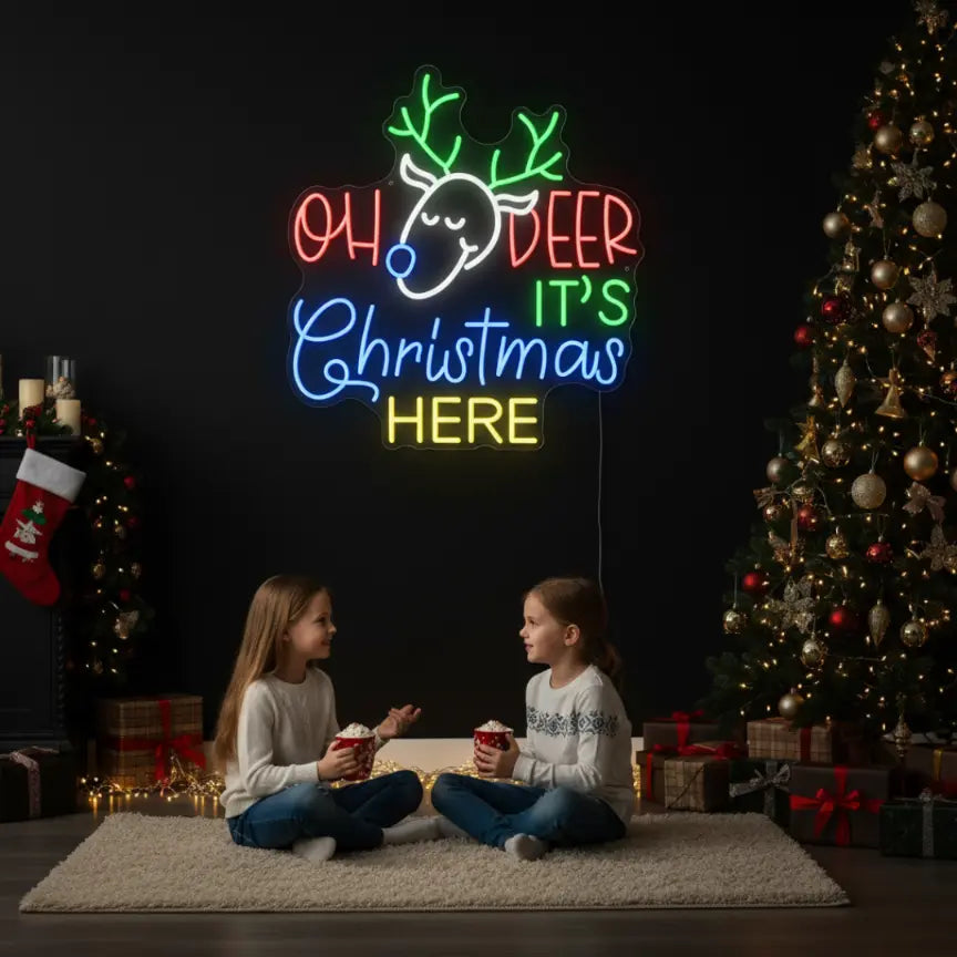 Photo of the 'Oh Deer It's Christmas Here' neon sign glowing in cool white against a styled interior wall.