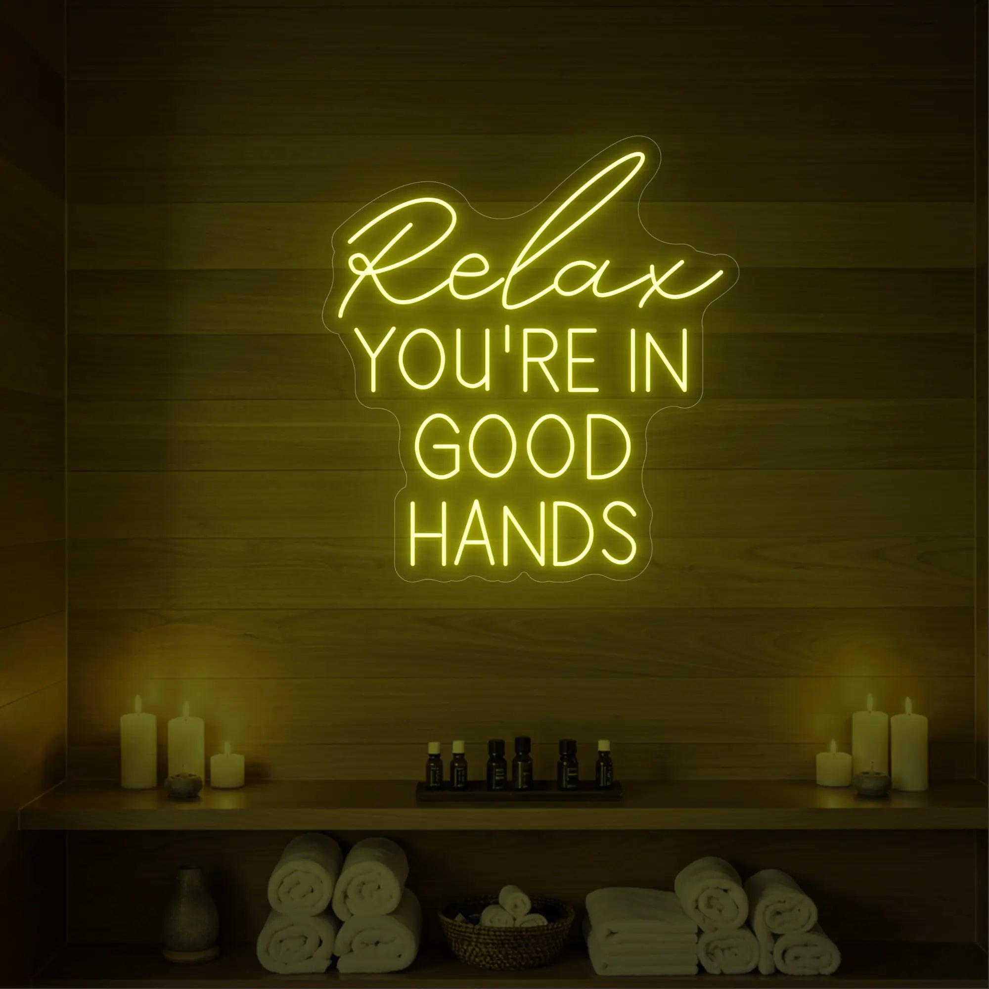 Photo of the 'Relax You're in Good Hands' neon sign glowing in lemon yellow against a styled interior wall.