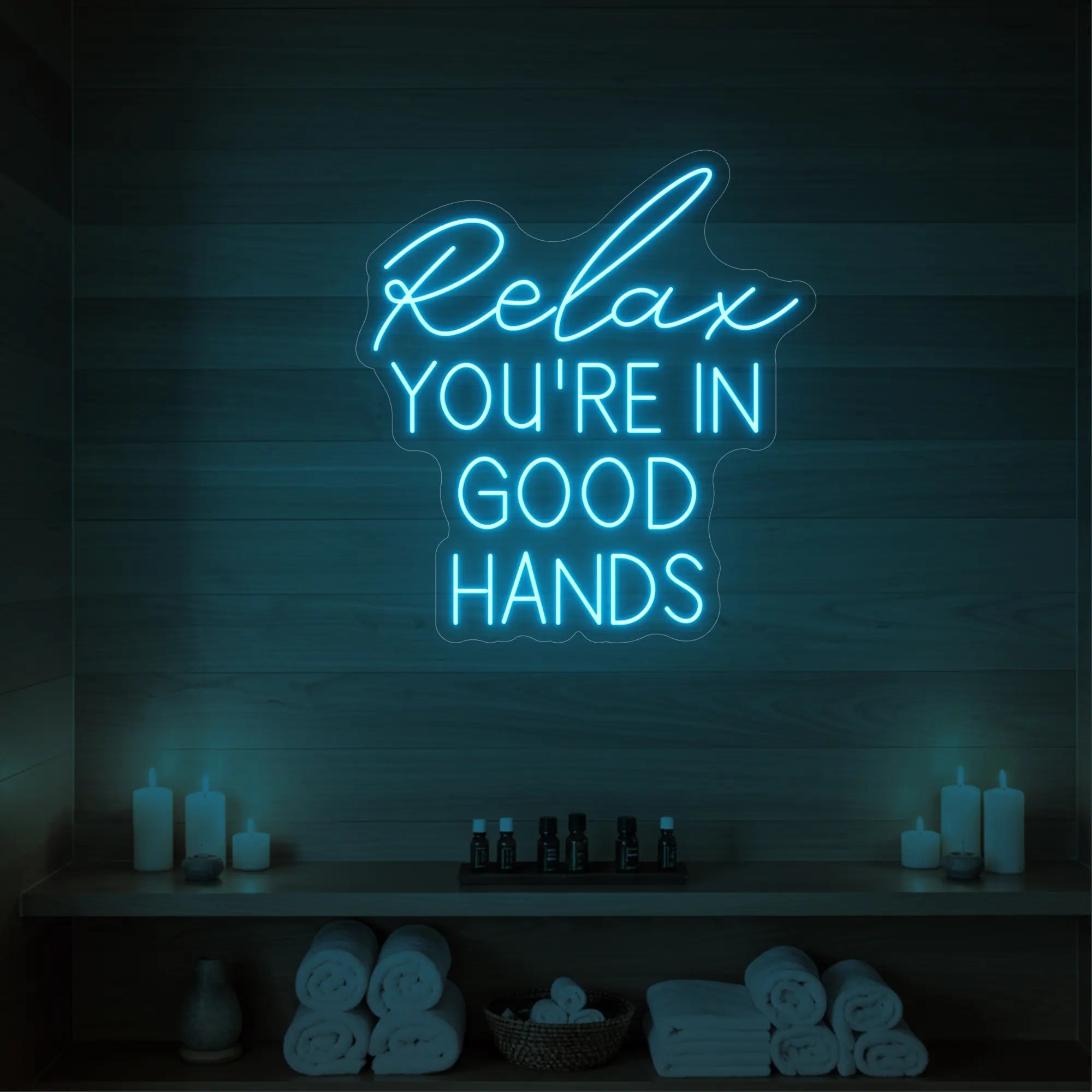 Photo of the 'Relax You're in Good Hands' neon sign glowing in ice blue against a styled interior wall.