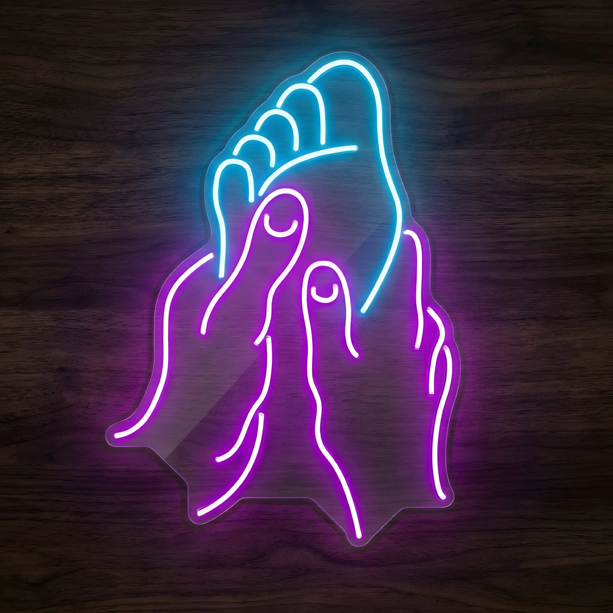 Relaxing Foot Treatment LED Neon Sign featuring a bright blue foot outline supported by glowing purple hands on clear cut-to-shape acrylic against a dark wooden wall.