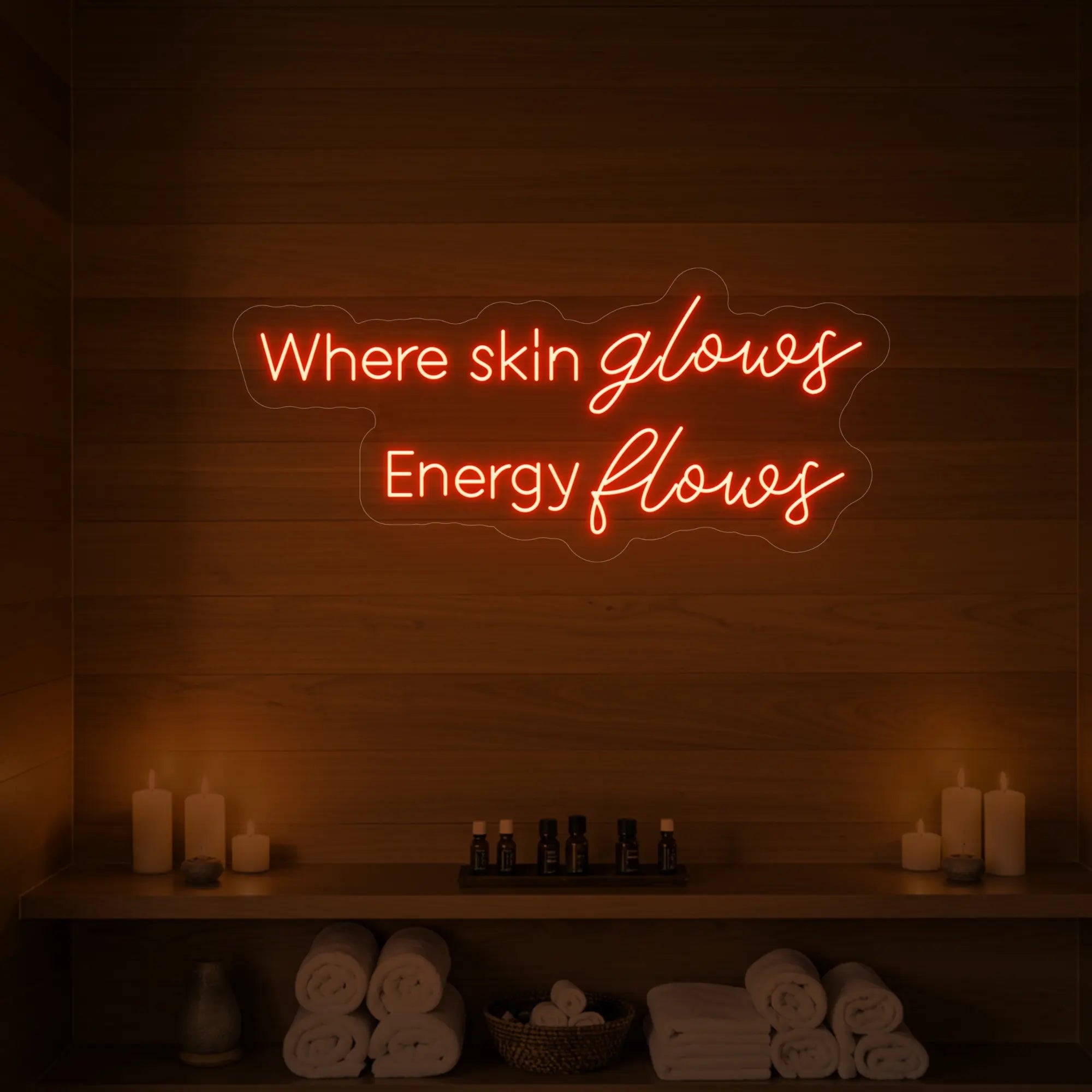 Photo of the 'Where Skin Glows, Energy Flows' neon sign glowing in golden yellow against a styled interior wall.