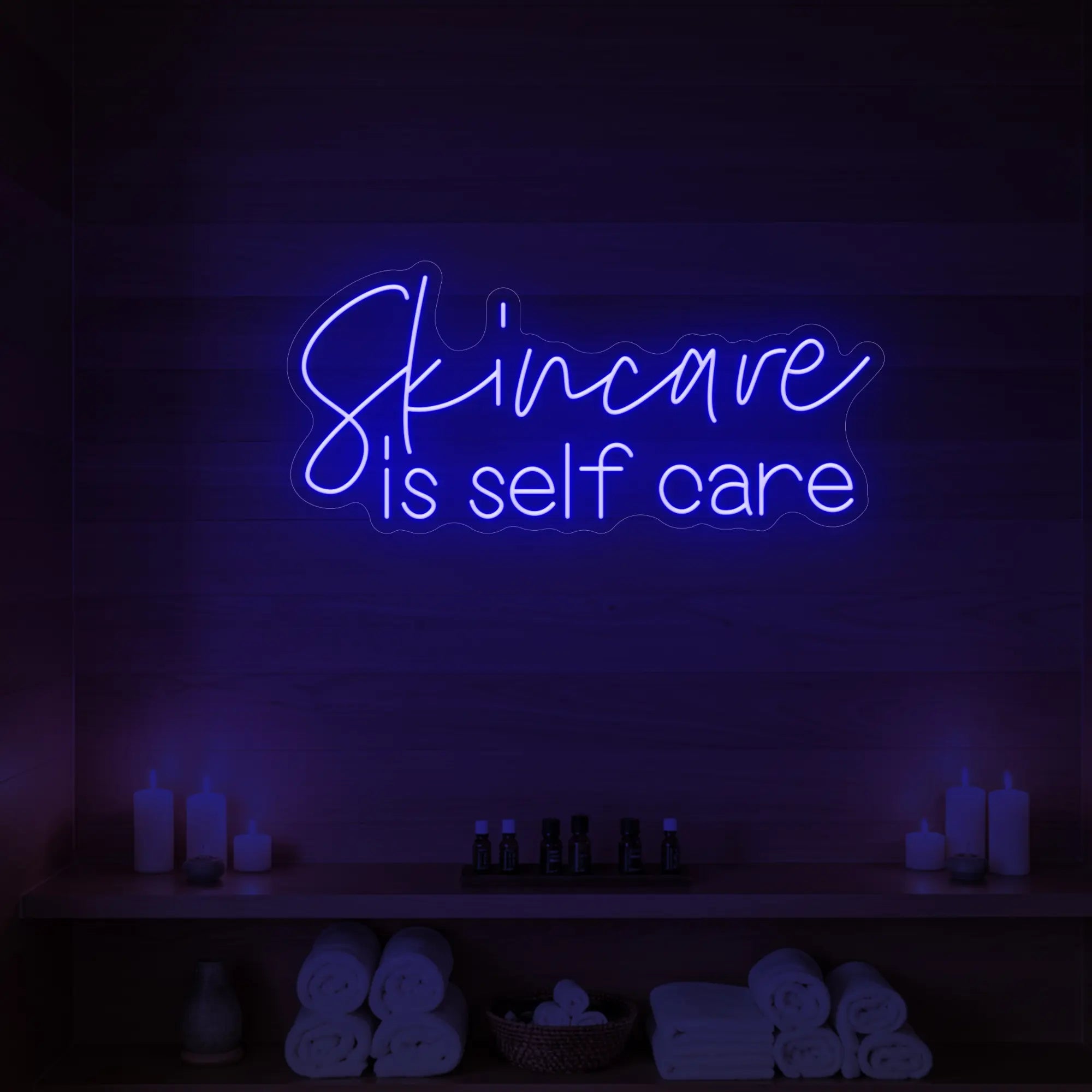Photo of the 'Skincare is Self Care' neon sign glowing in deep blue against a styled interior wall.