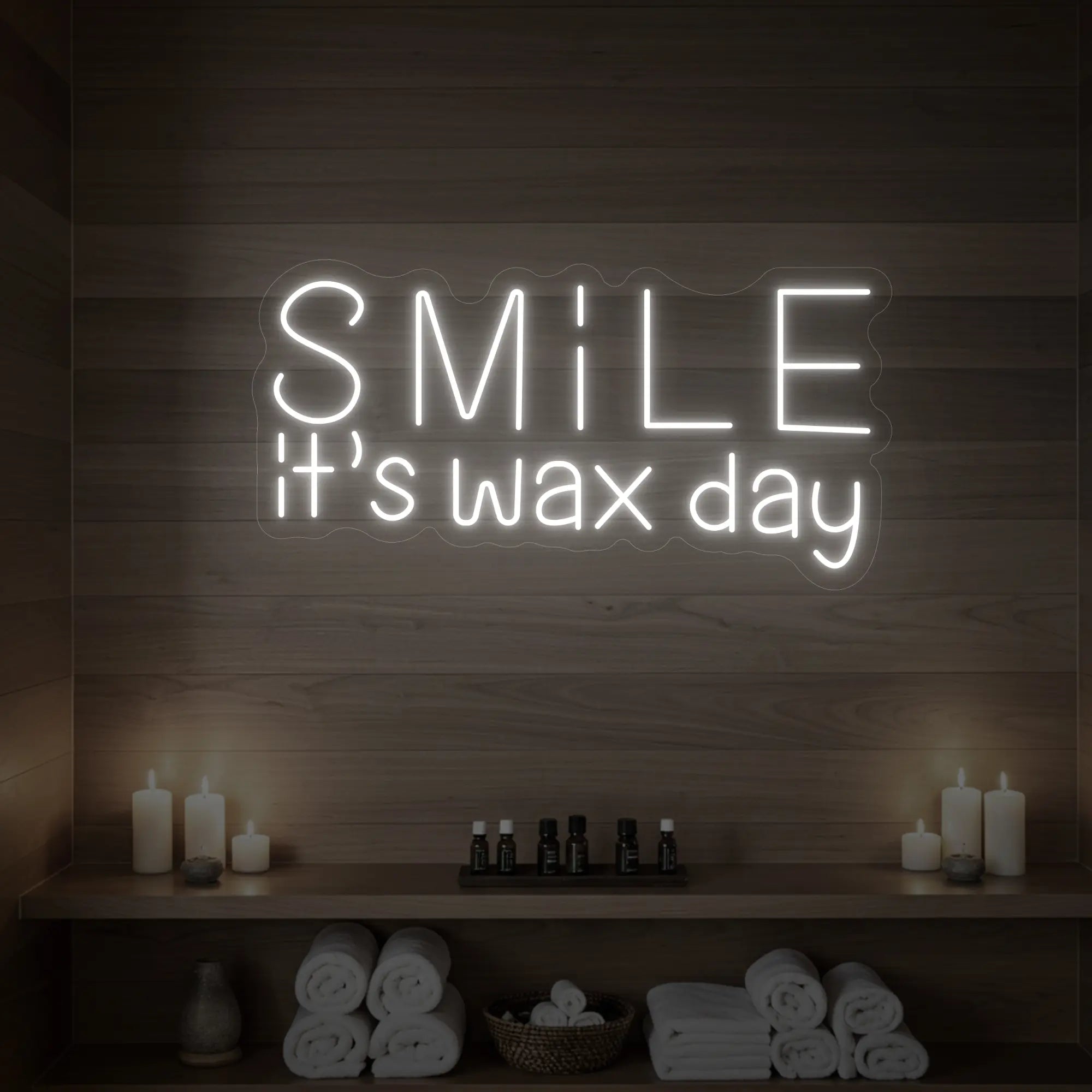 Photo of the 'Smile It’s Wax Day' neon sign glowing in cool white against a styled interior wall.