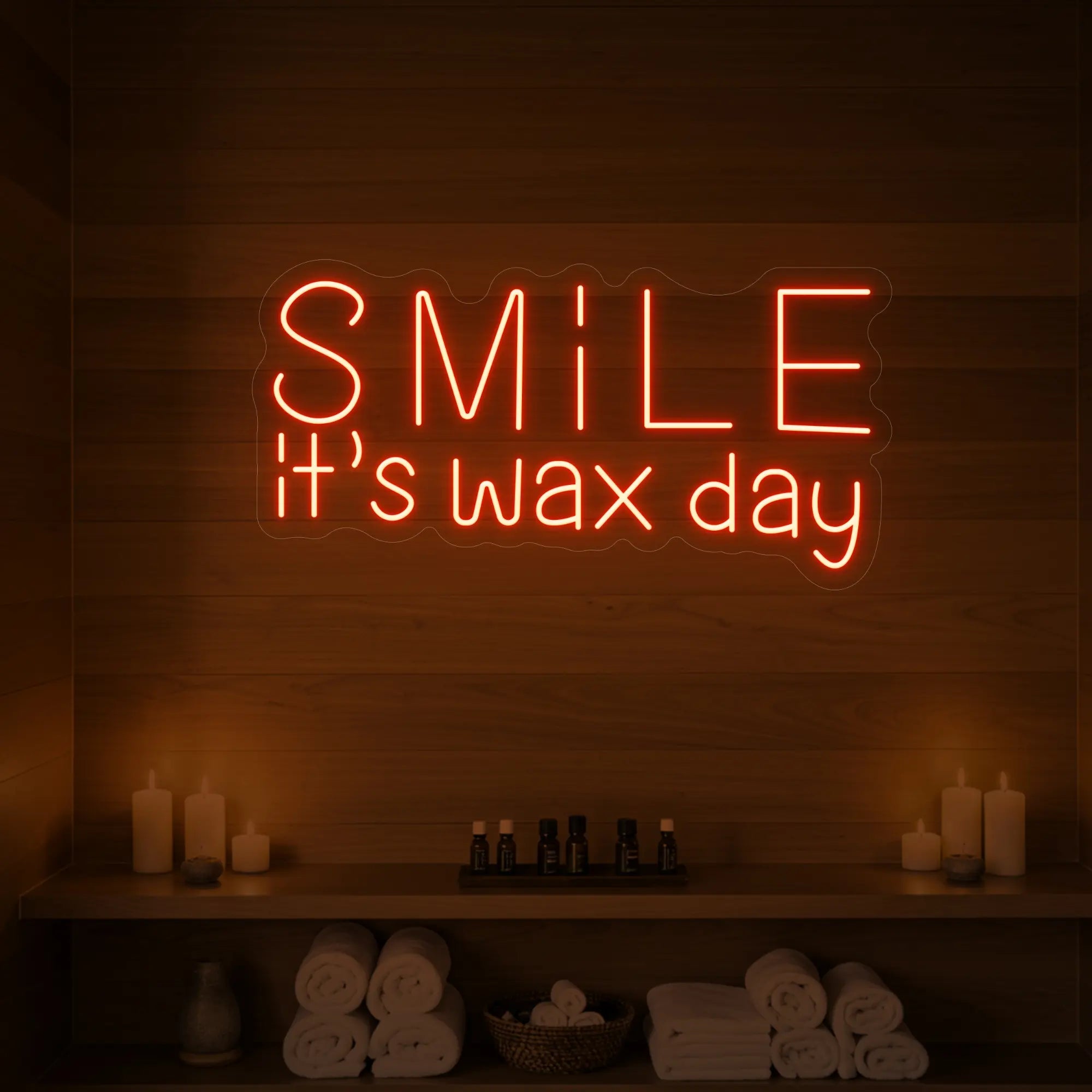 Photo of the 'Smile It’s Wax Day' neon sign glowing in golden yellow against a styled interior wall.
