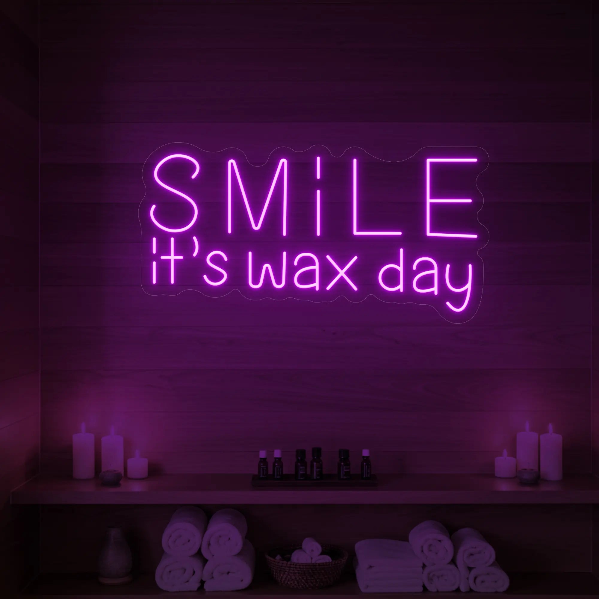 Photo of the 'Smile It’s Wax Day' neon sign glowing in deep pink against a styled interior wall.