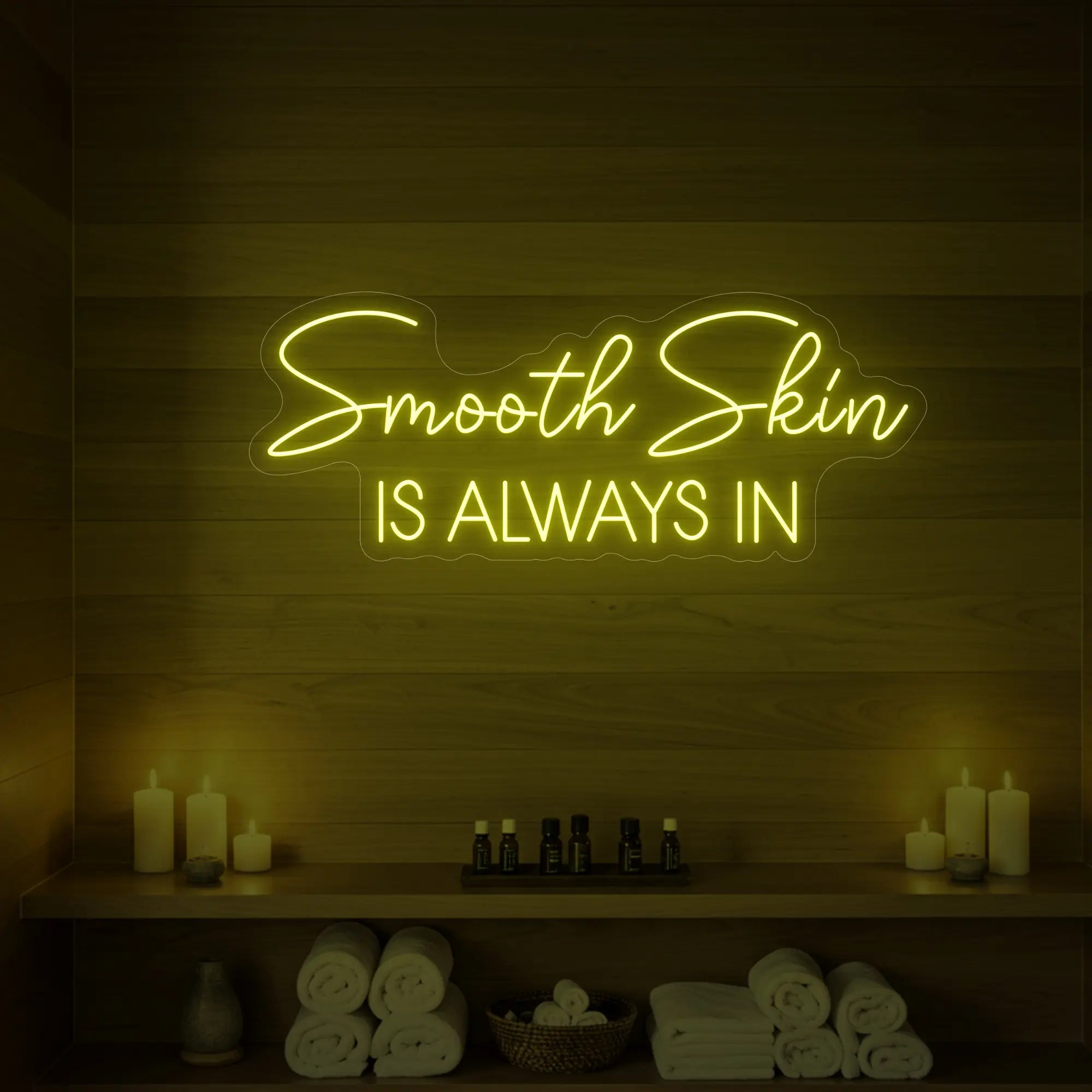 Photo of the 'Smooth Skin Is Always In' neon sign glowing in lemon yellow against a styled interior wall.