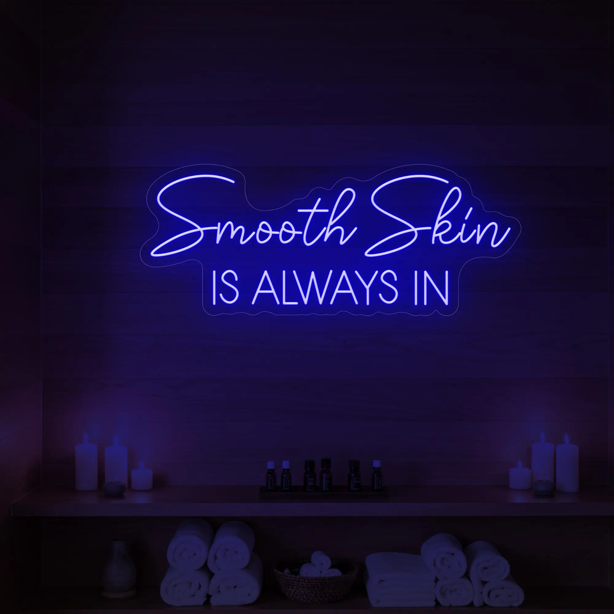 Photo of the 'Smooth Skin Is Always In' neon sign glowing in deep blue against a styled interior wall.