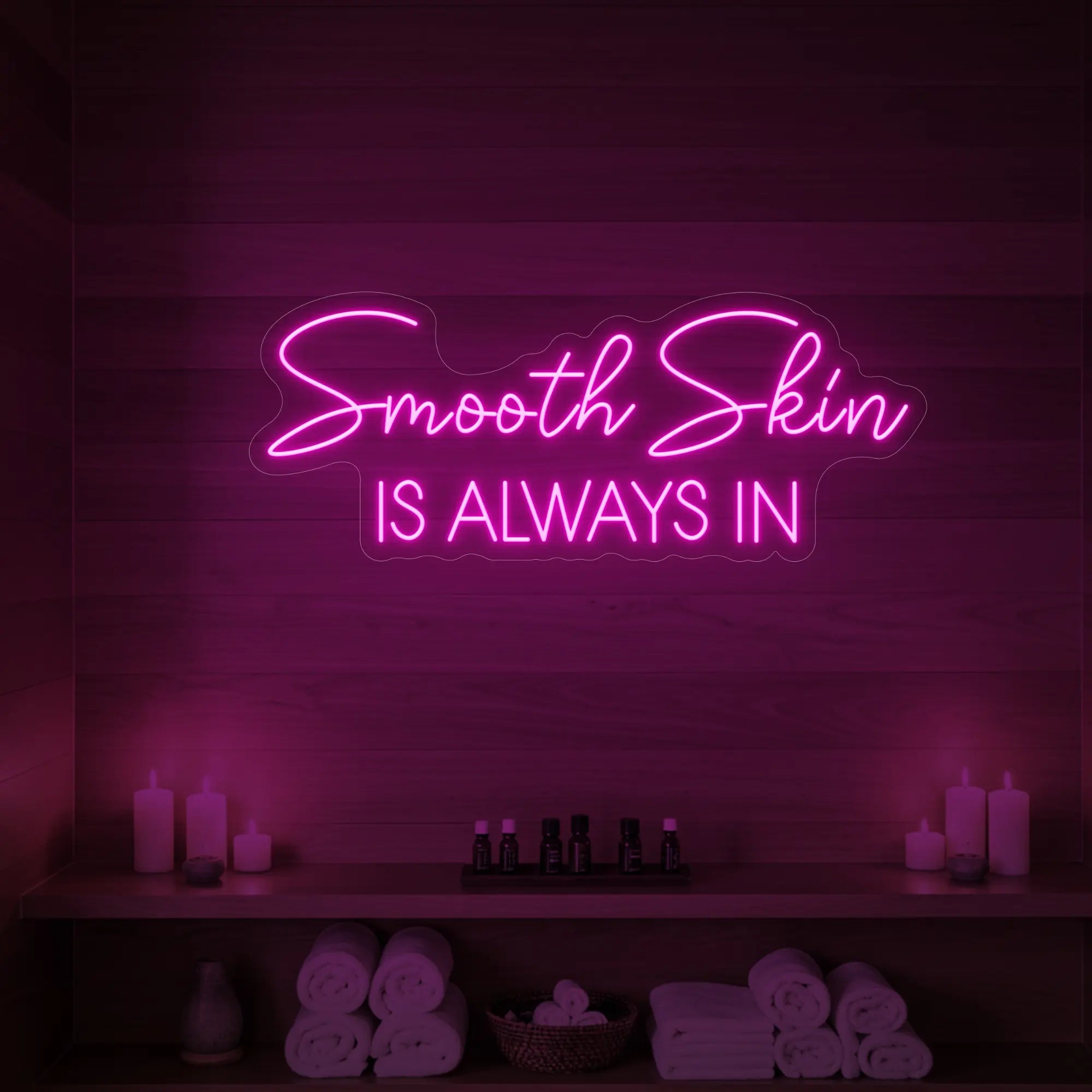 Photo of the 'Smooth Skin Is Always In' neon sign glowing in light pink against a styled interior wall.