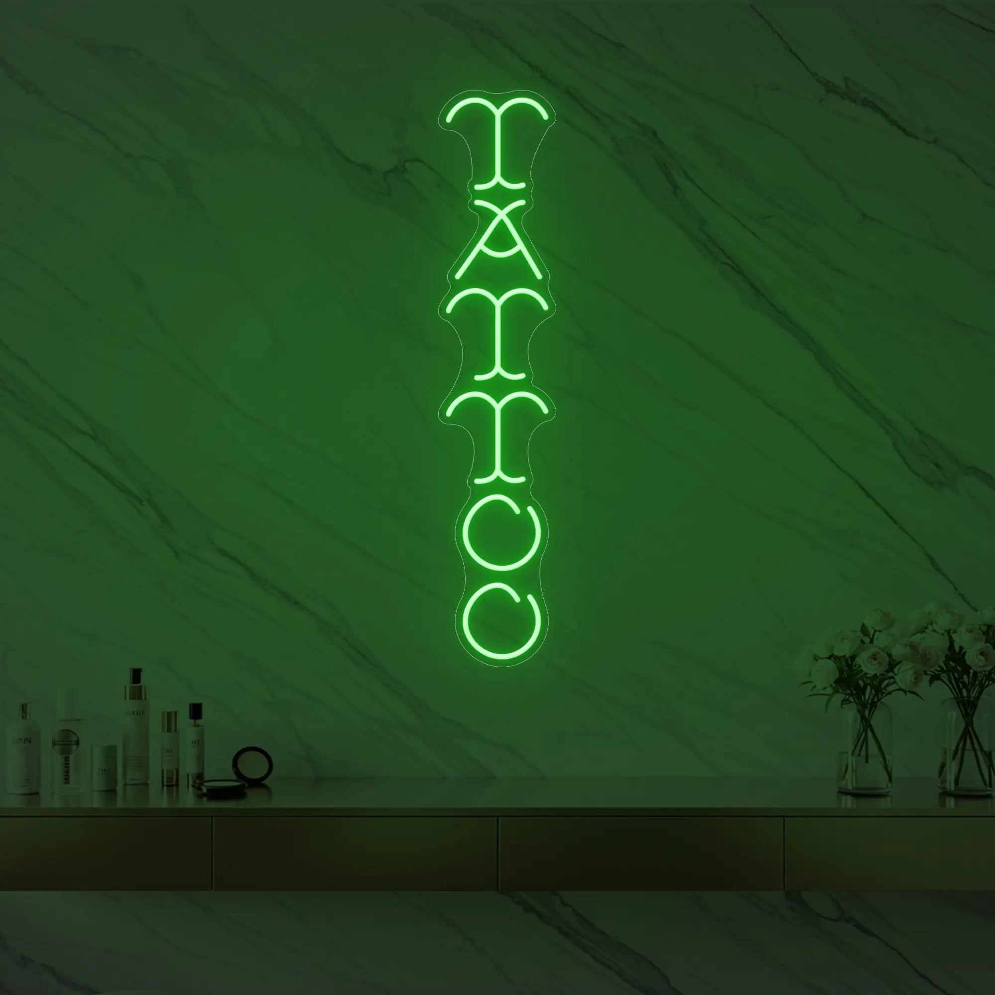 Photo of the 'Vertical Tattoo' neon sign glowing in green against a styled interior wall.